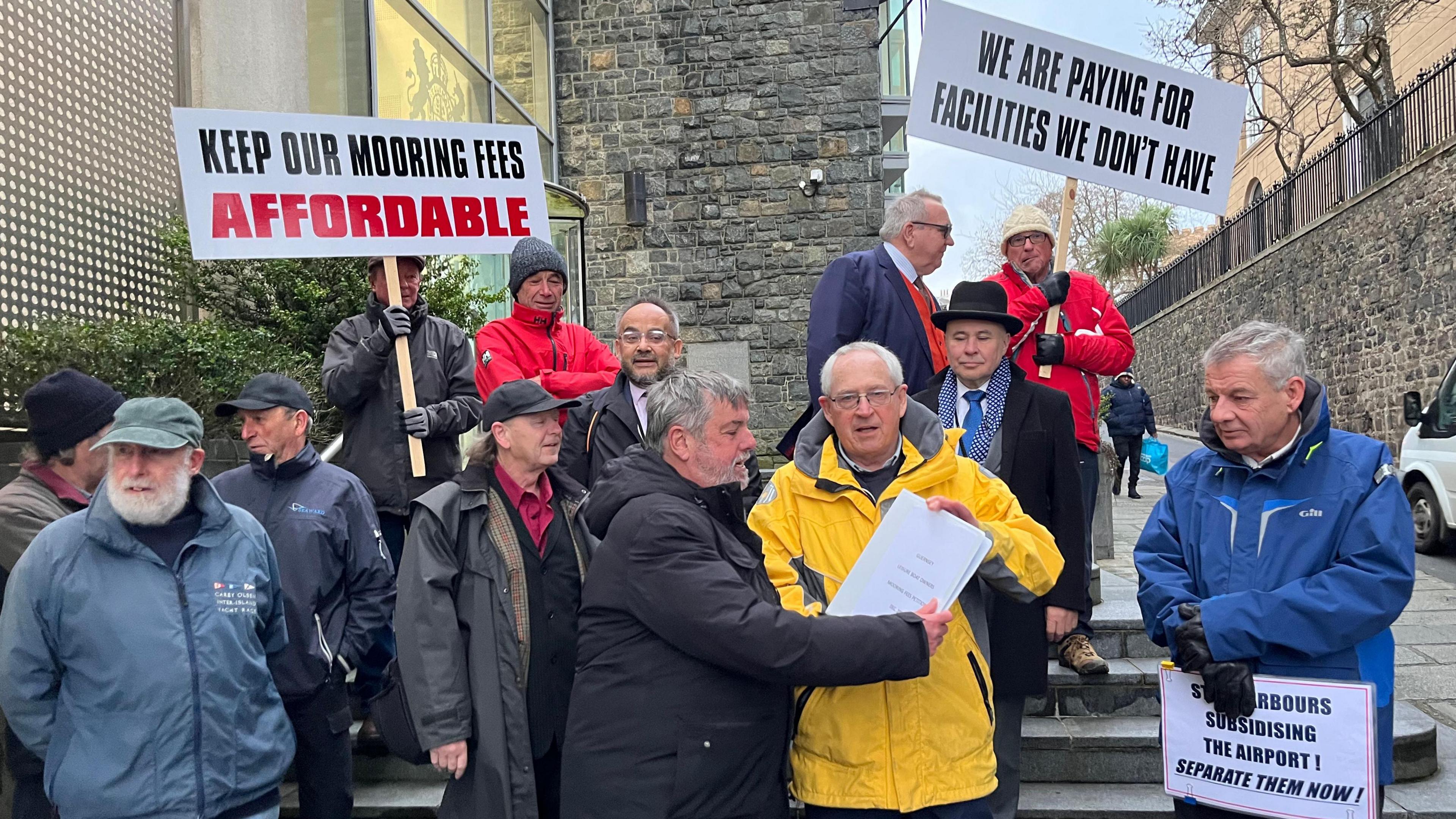 Thirteen men holding signs standing on the steps of Guernsey's Royal Court