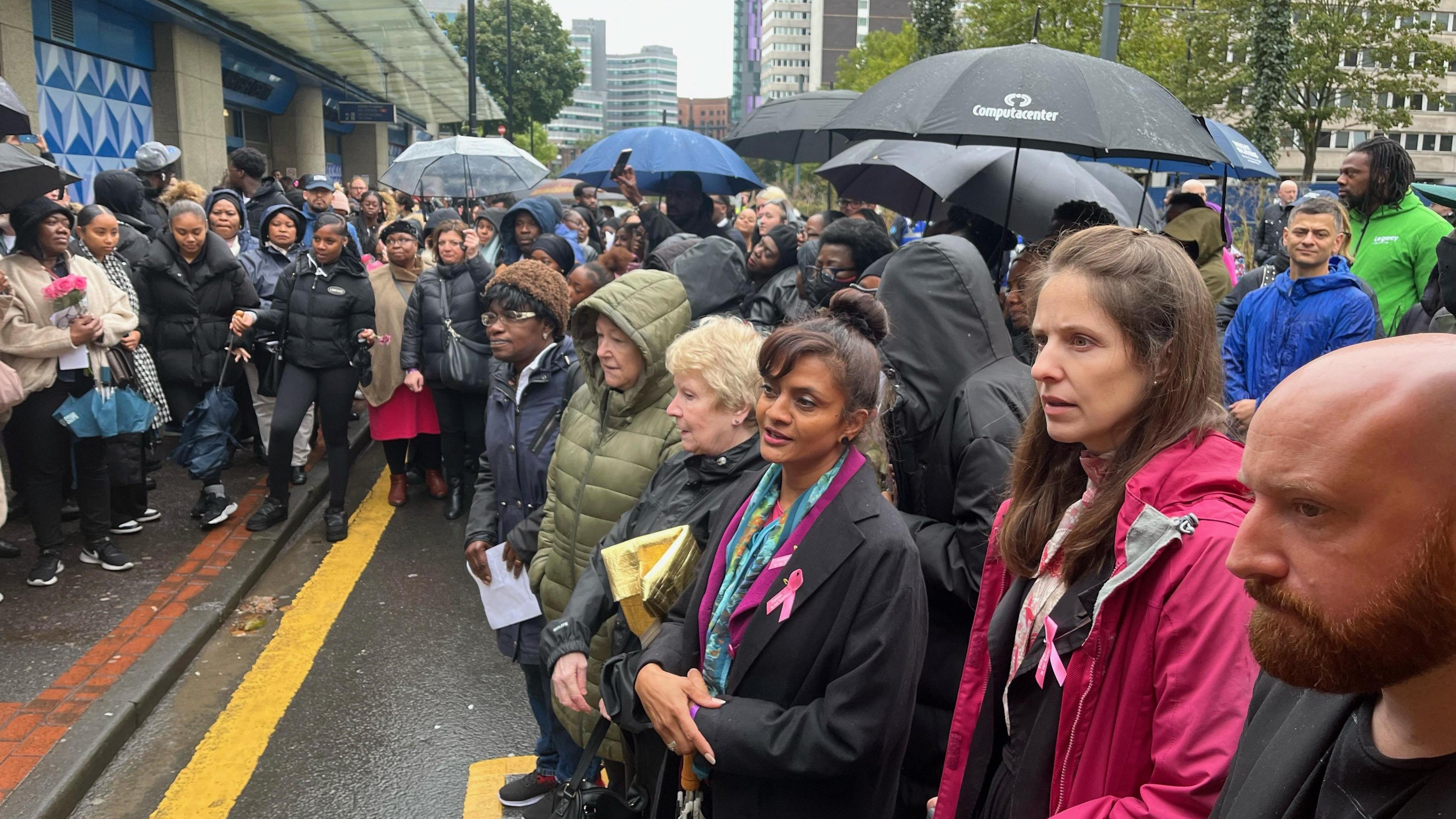 People gathering in the rain at the memorial unveiling of Elianne Andam