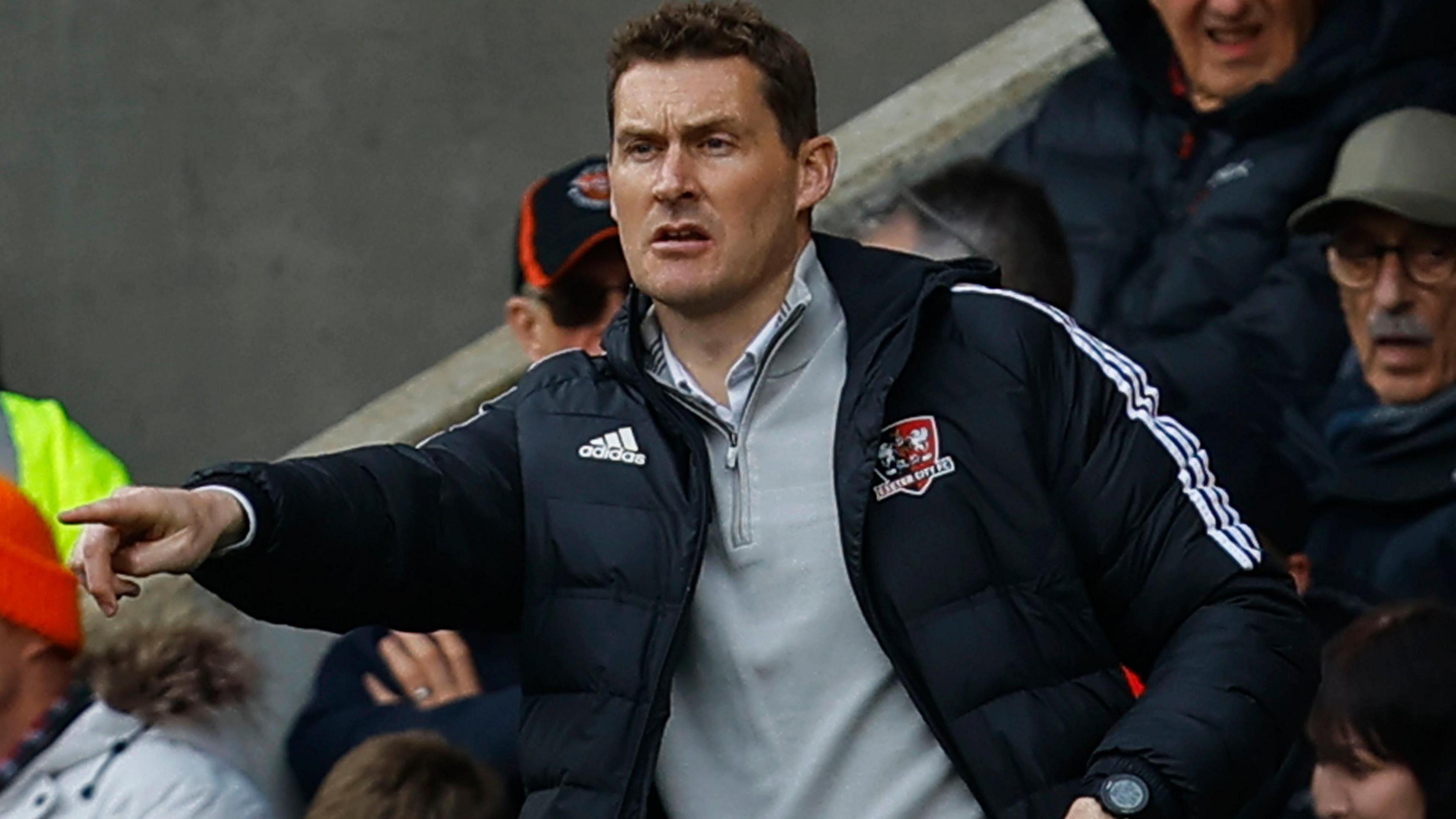 Exeter City boss Matt Taylor pointing towards one of his players by the touchline during the match.
