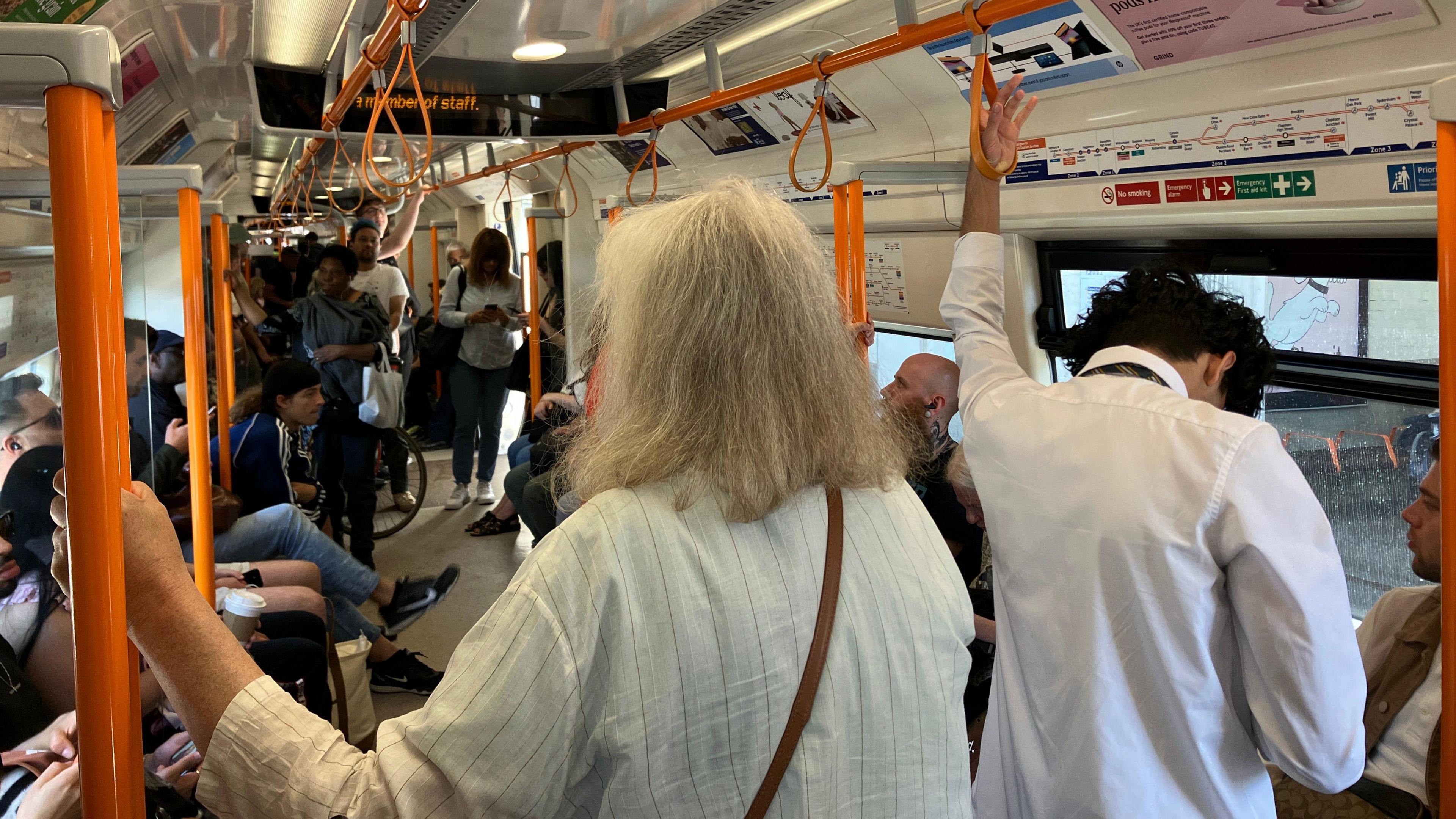 Passengers stand inside an Overground train