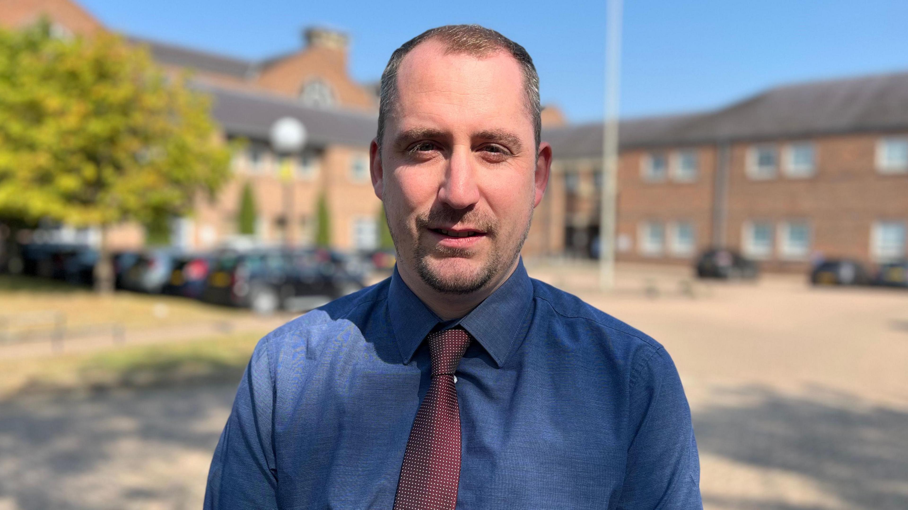 Detective Sergeant Ricki Peake wearing a blue shirt and red tie outside Norwich Crown Court