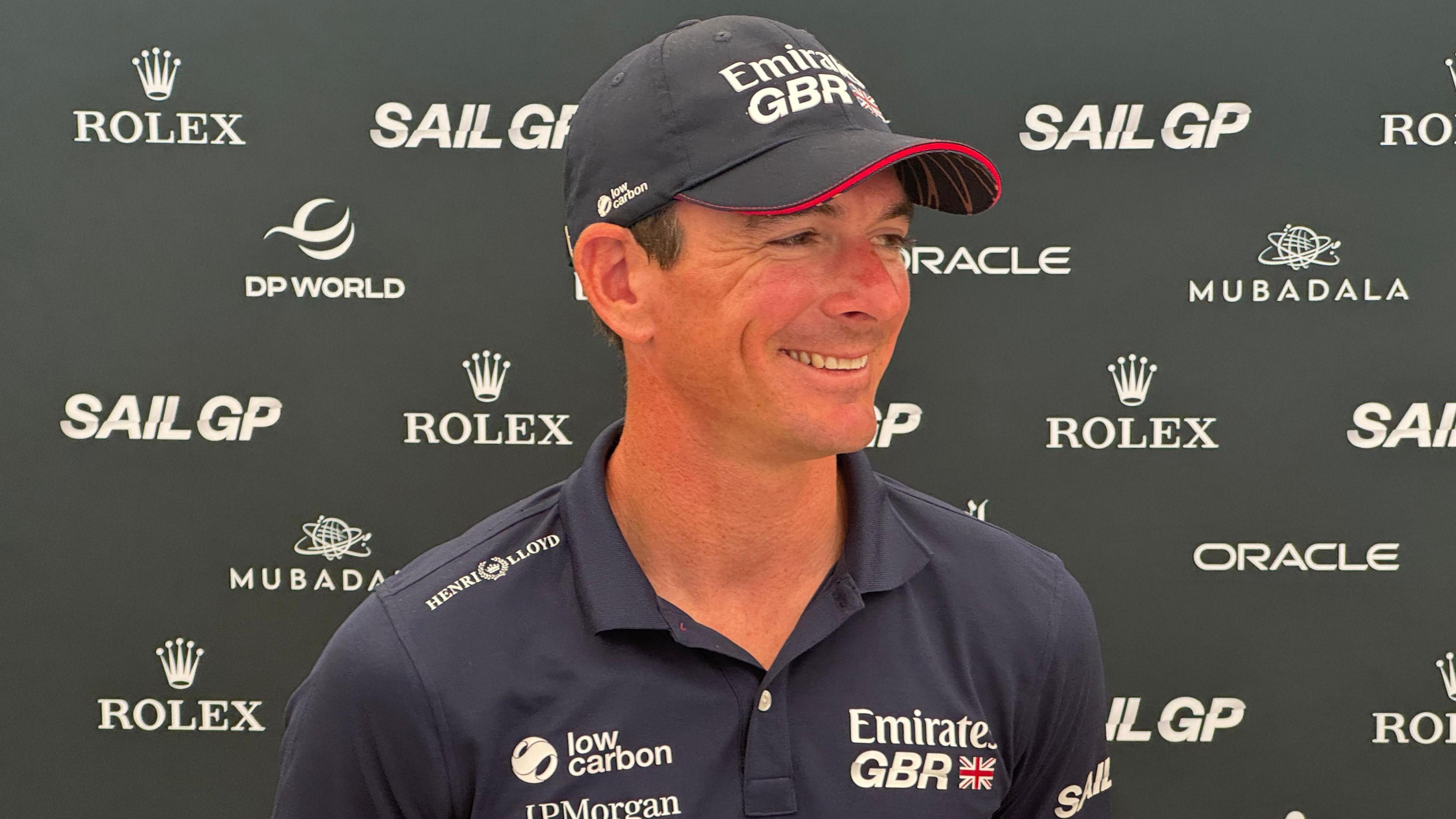 Dylan Fletcher, wearing a GBR cap and t-shirt and stood in front of an advertising board