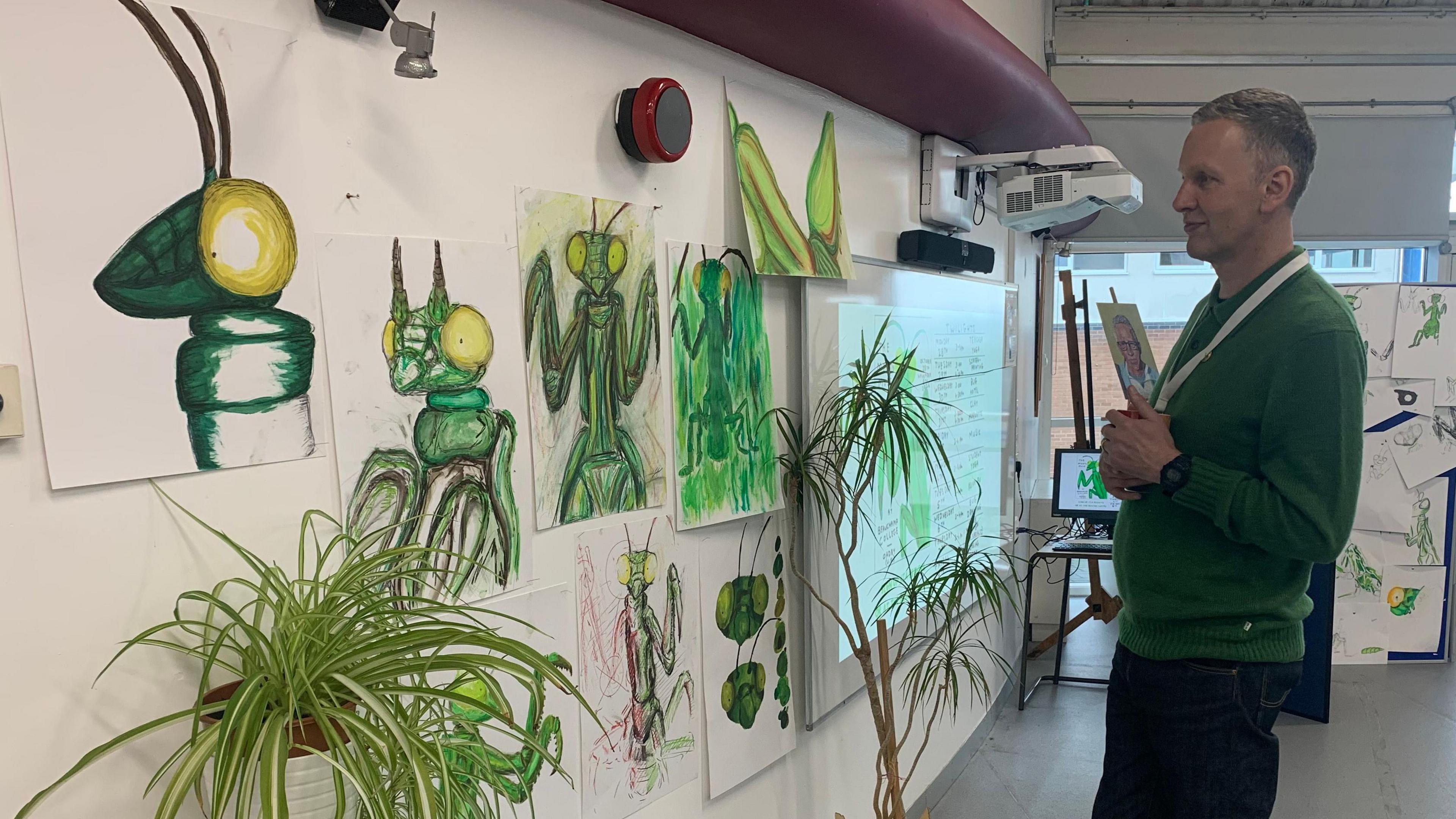 David Shrigley looking at some of the drawings of The Mantis Muse by students at Beauchamp College, in Oadby, Leicestershire