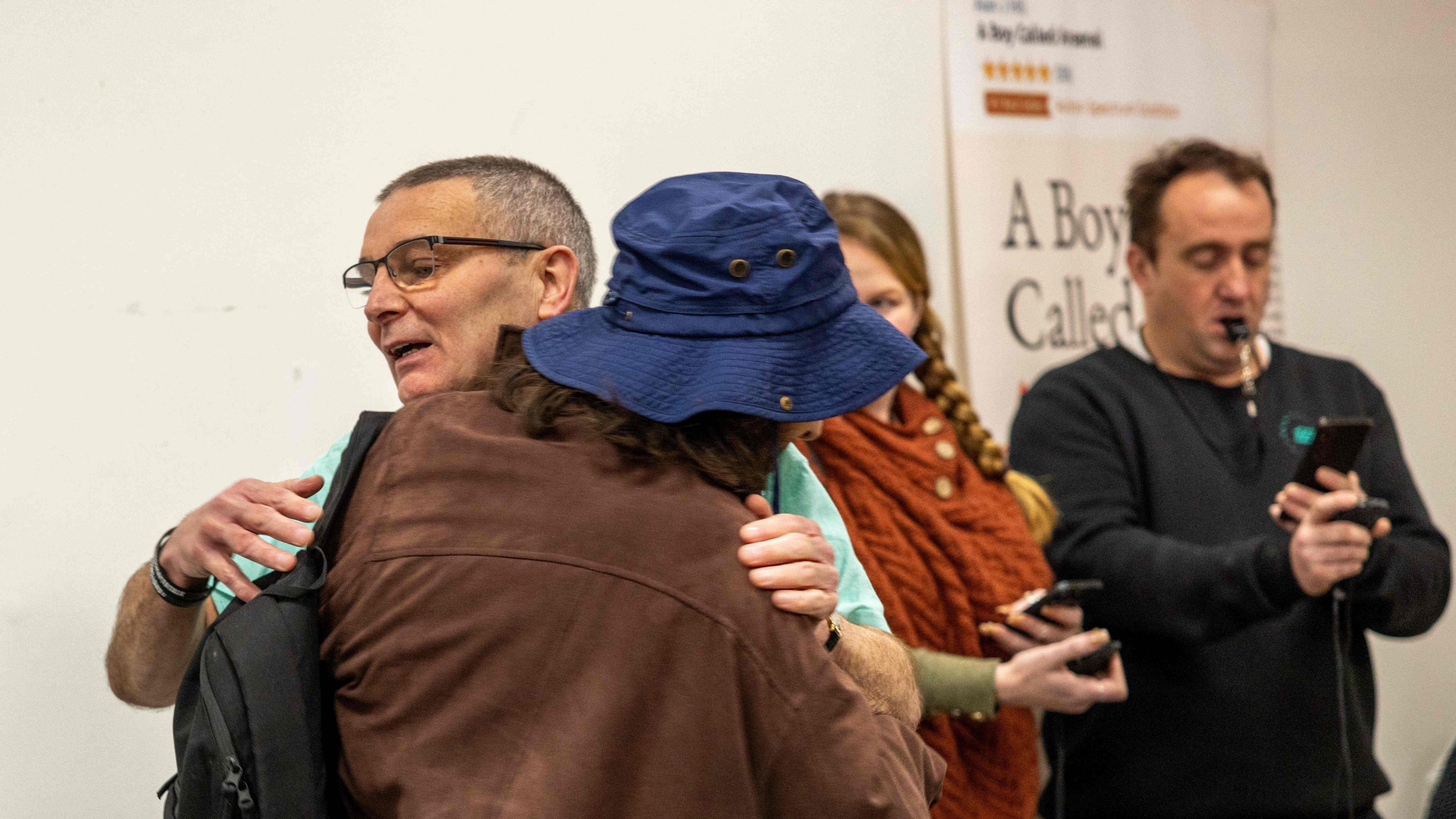 Arsenal Whittick hugging an unidentifiable person. Behind them is a man with a stopwatch.