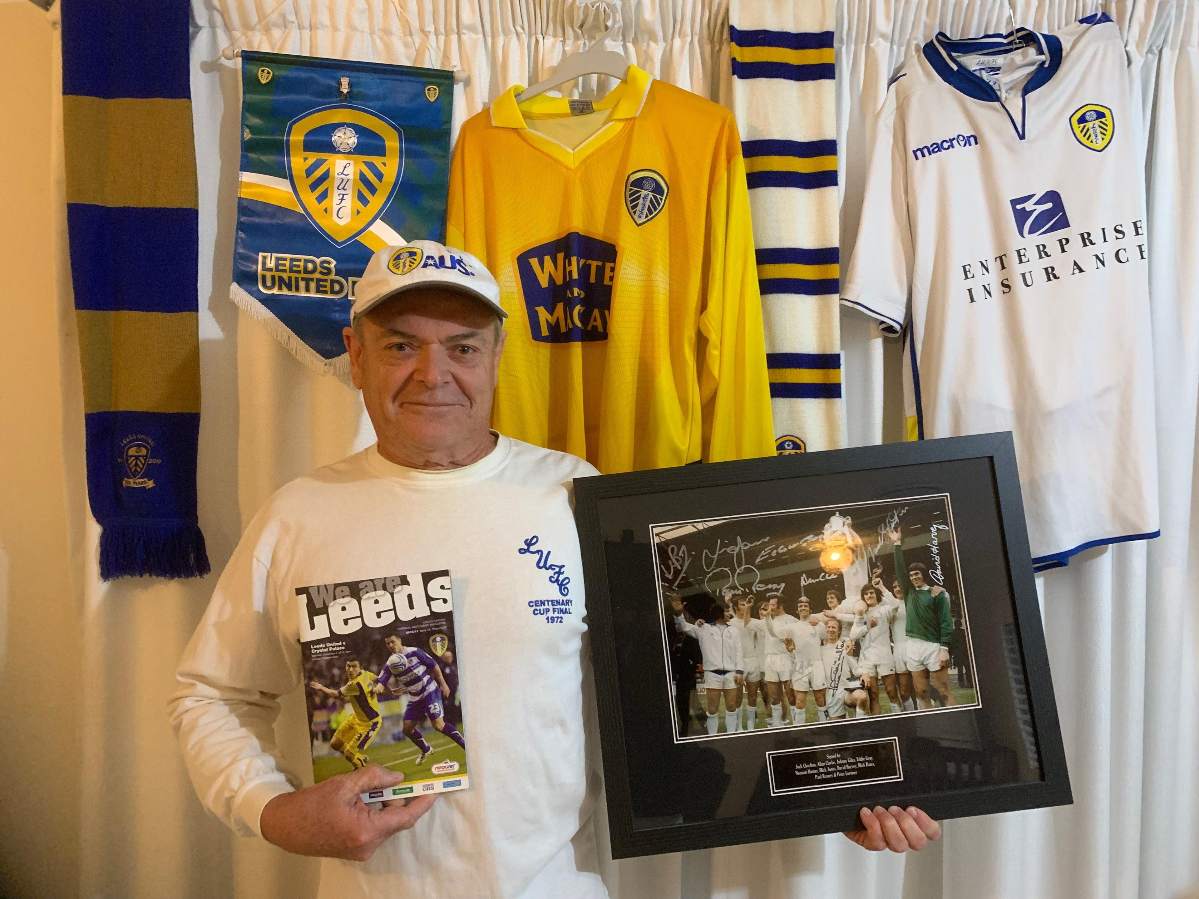 A picture of a man with two Leeds shirts, a programme, a scarf and a signed photograph