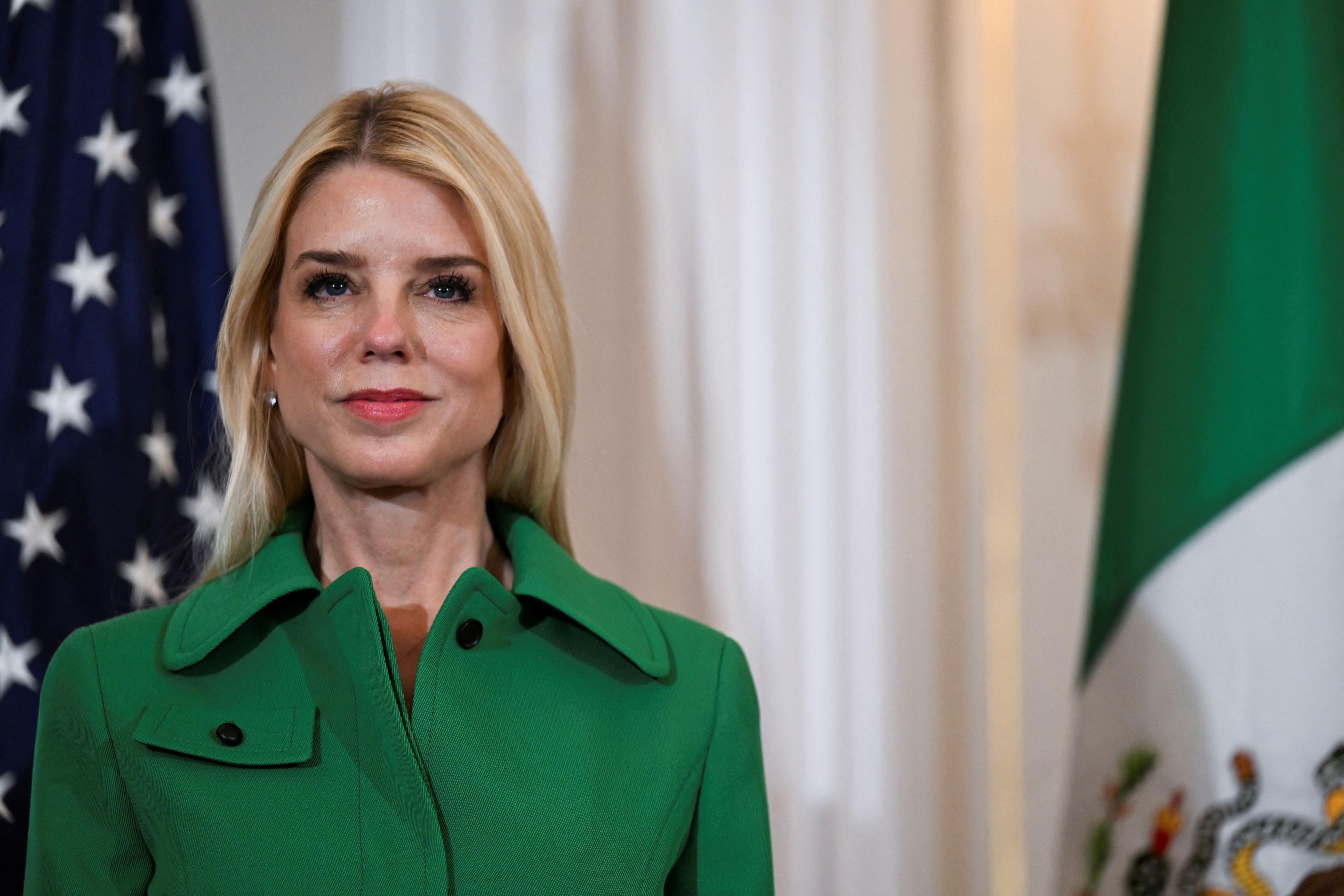 The attorney general in a green dress standing in front of flags