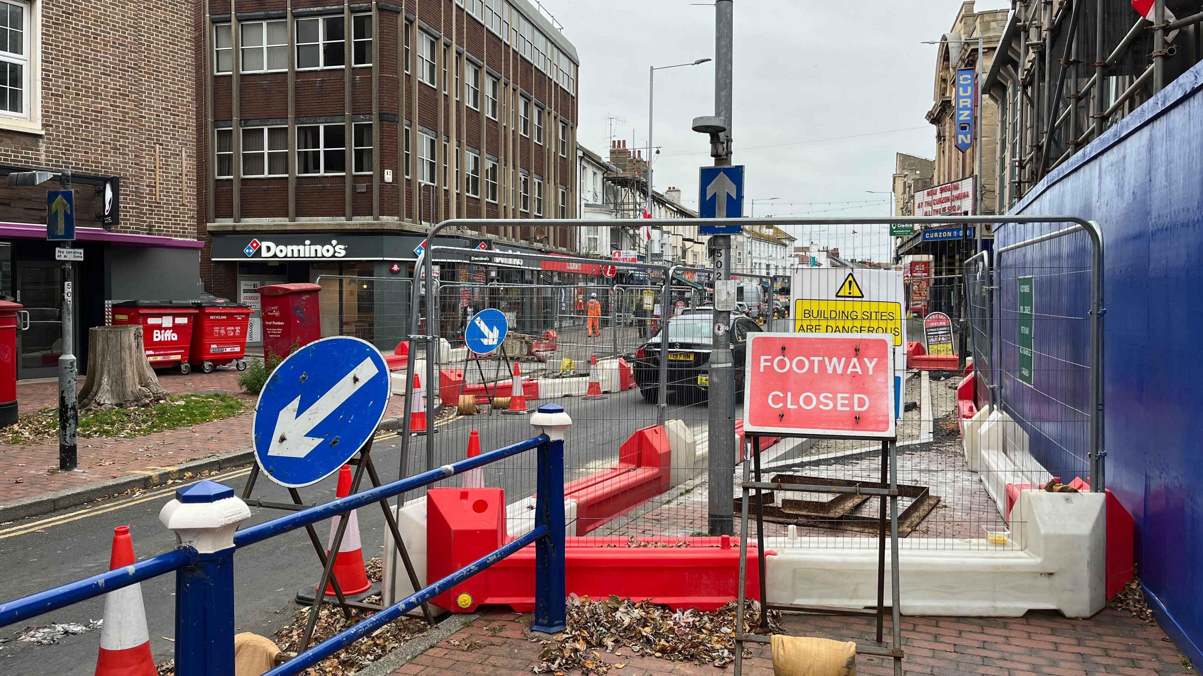 Fencing set up next to a scaffolding structure which have blocked off the pavement. A red sign reads Footway closed 