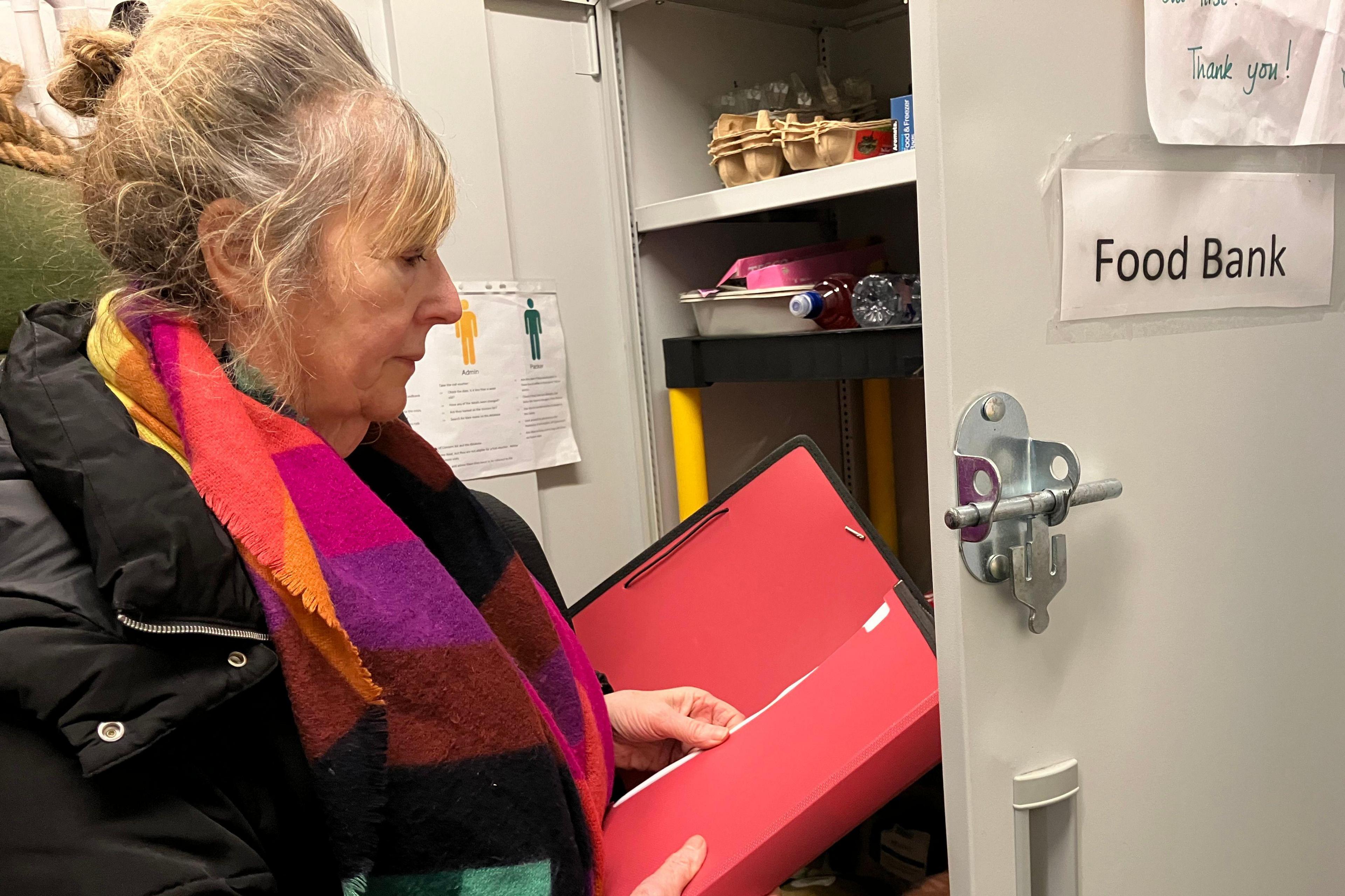 Fiona Nicol looking in foodbank cupboard while holding a folder.