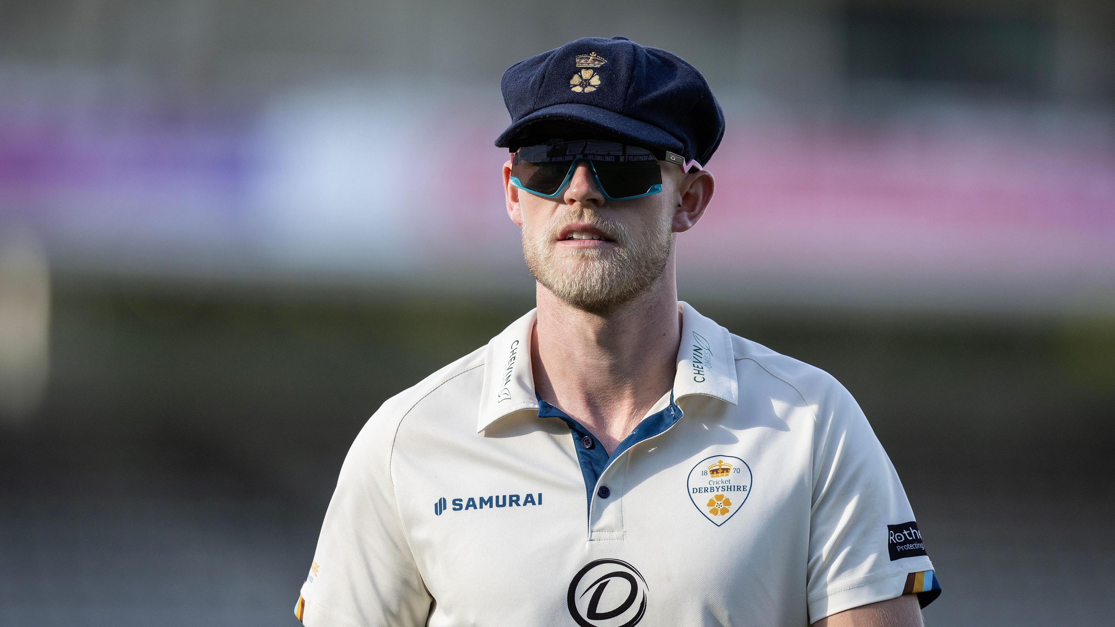 Derbyshire's Zak Chappell is wearing his baggy navy blue Derbyshire cap and sunglasses 