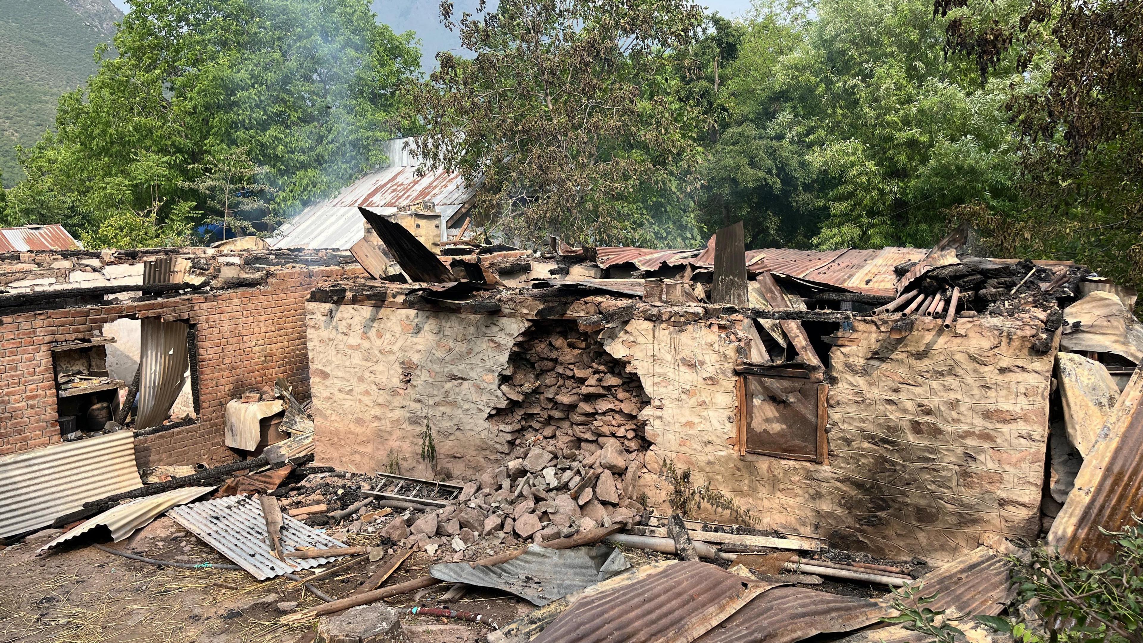 A stone home with a tin roof has a hole in its side