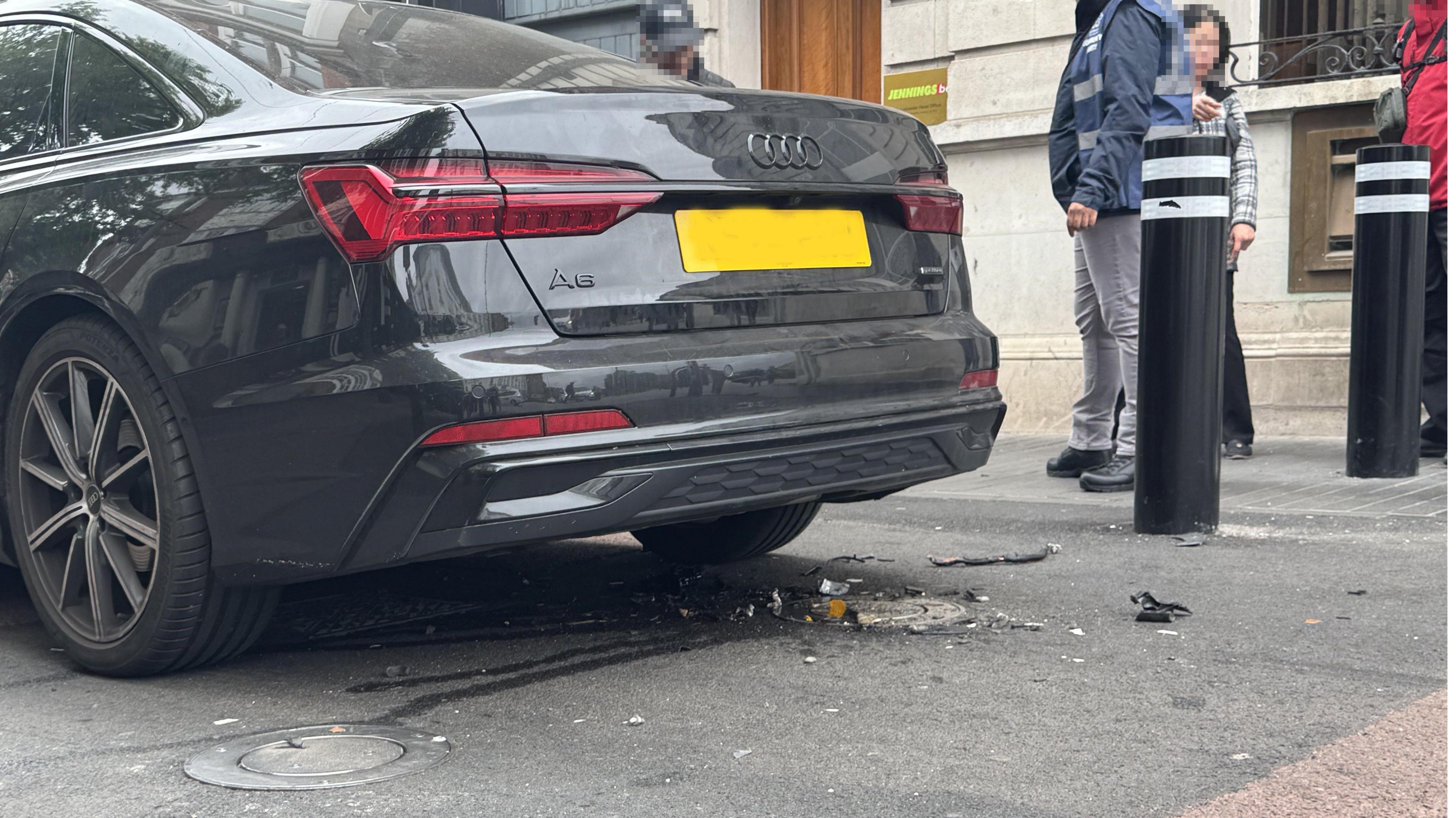 The back of a car hit by a rising bollard, with debris left on the road.
