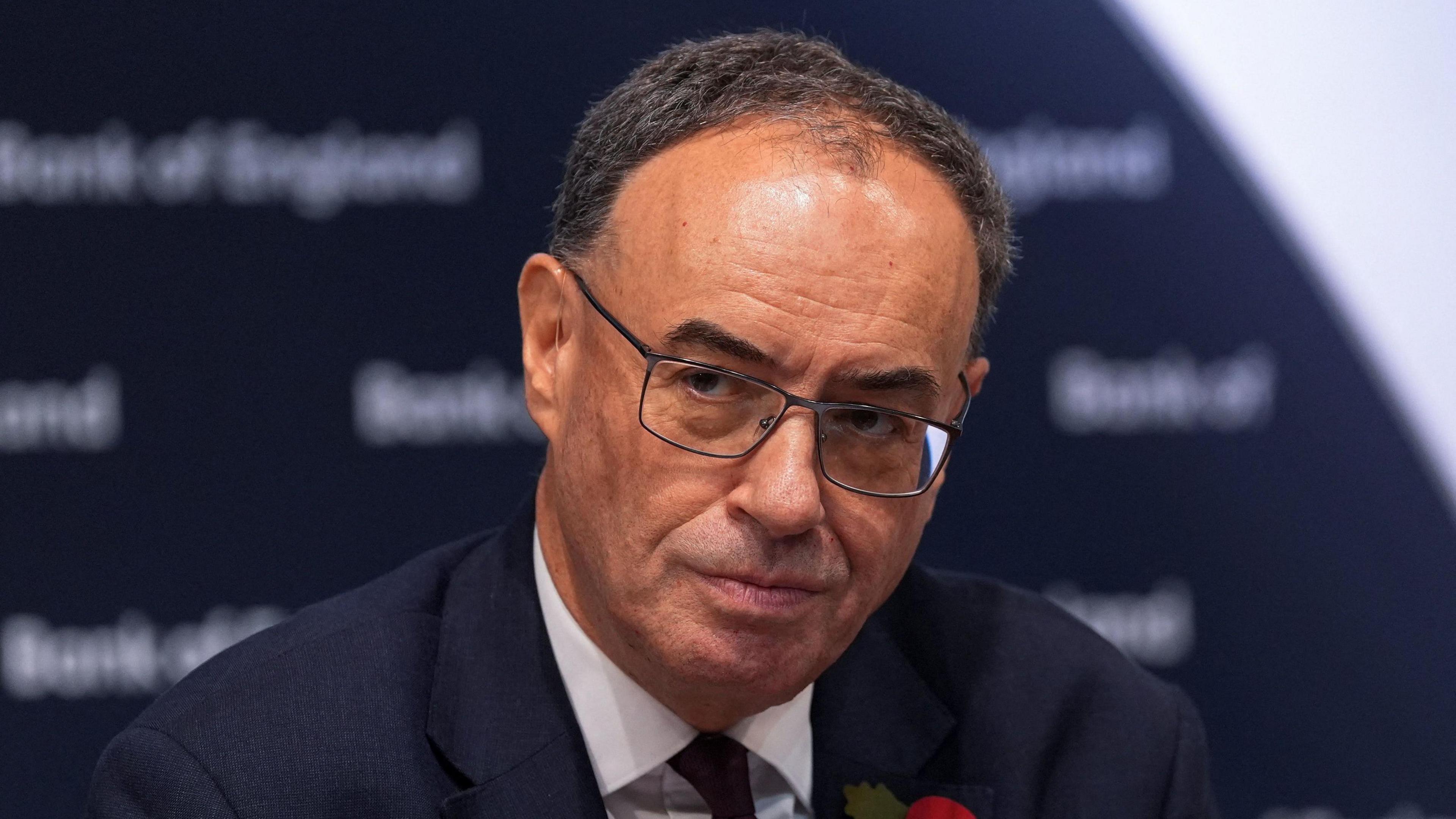 The Bank of England governor Andrew Bailey addresses a press conference wearing a dark suit and tie.