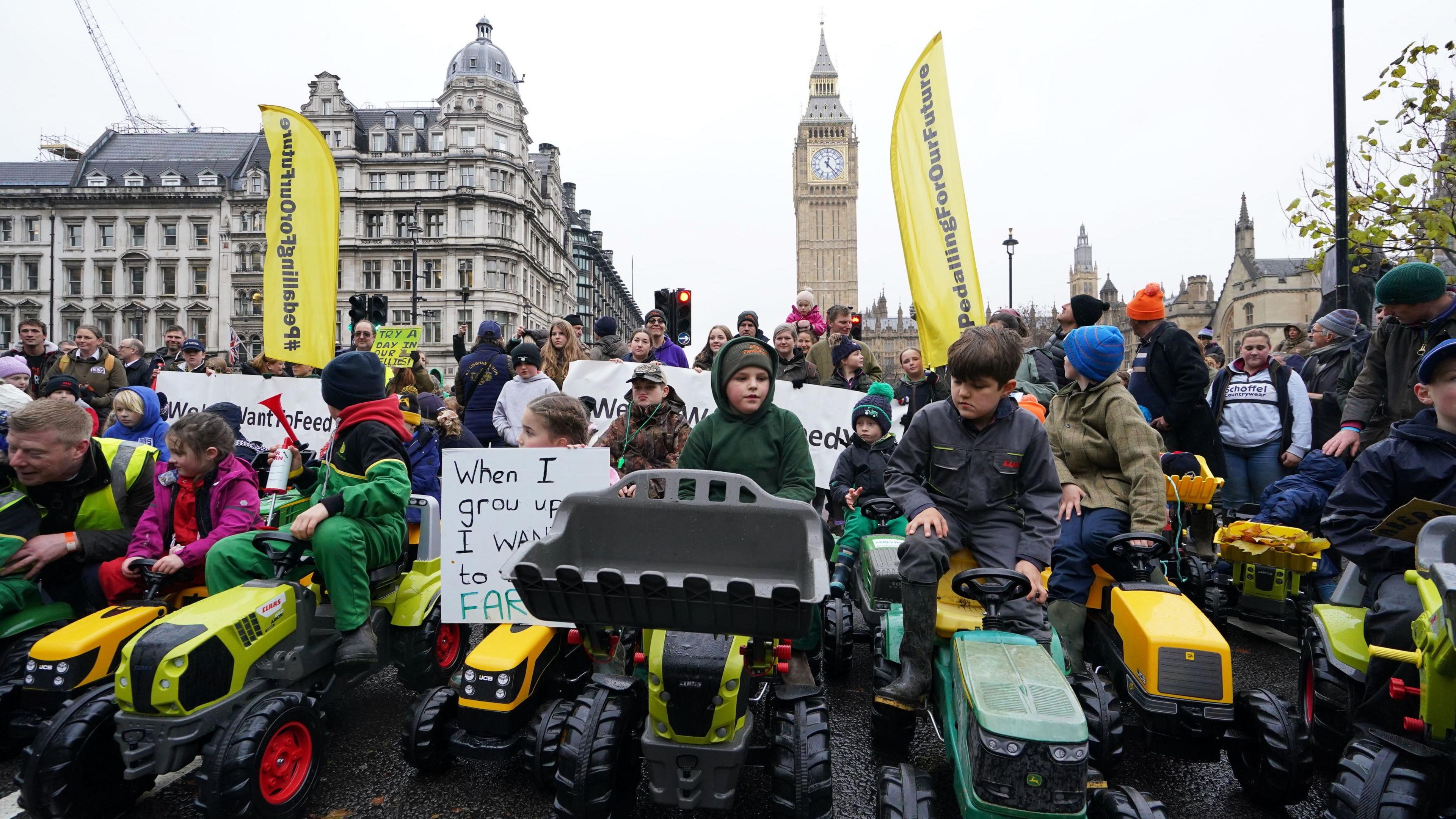 Children sat on toy tractors join the protest with the Queen Elizabeth Clock Tower on the Houses of Parliament in the background