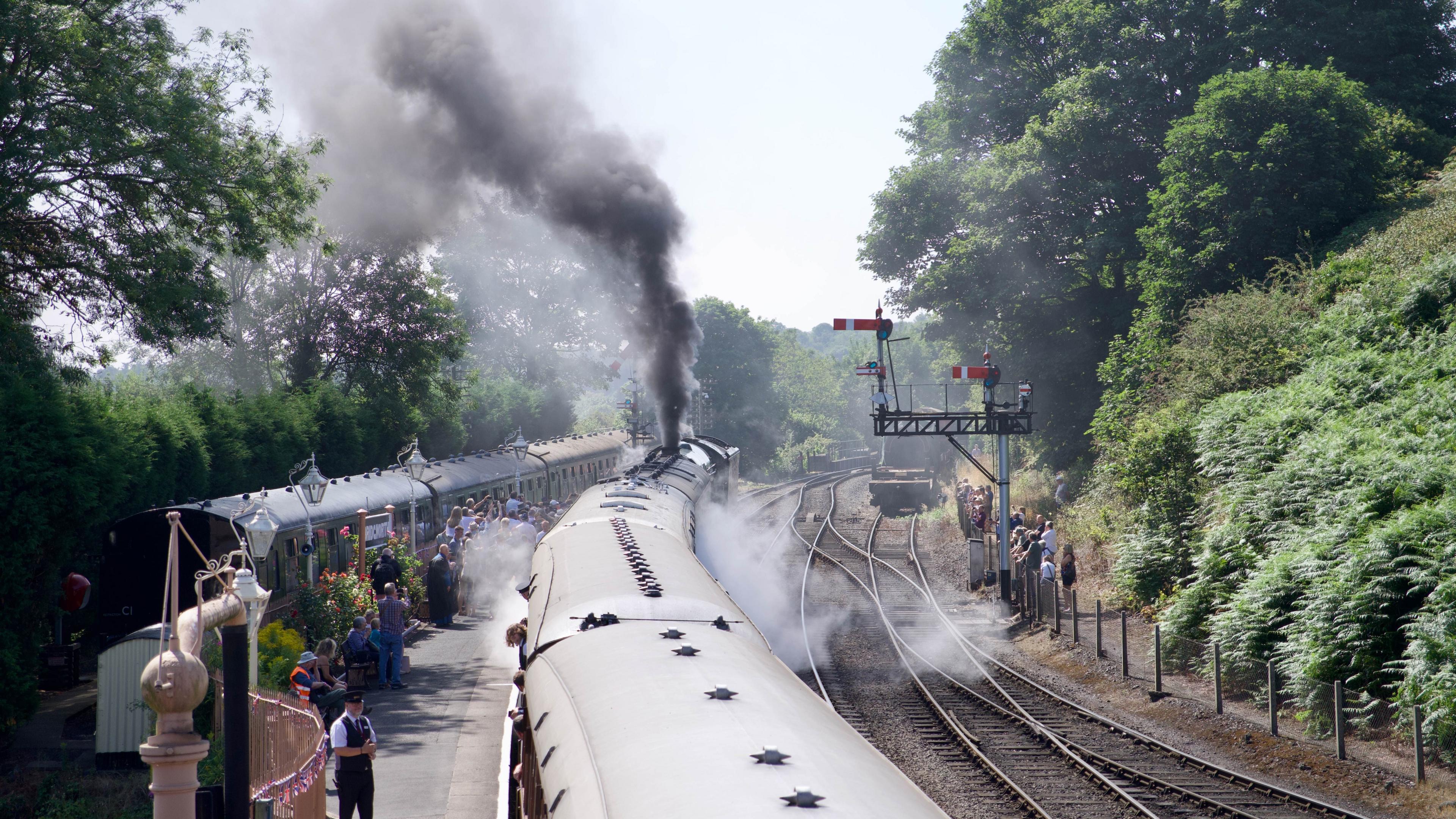 Grey smoke and steam rises into the air as Flying Scotsman departs from Bridgnorth Station.