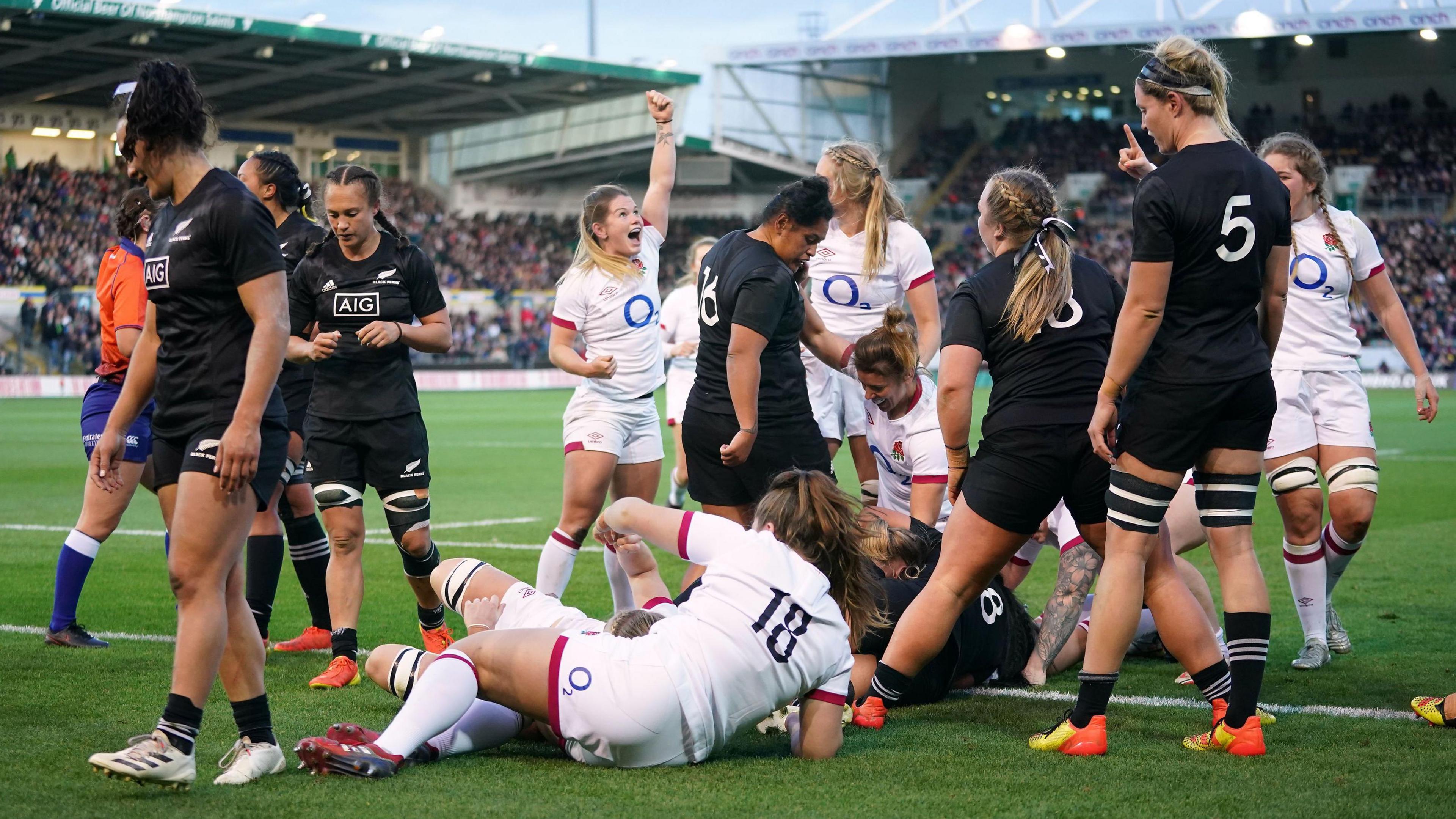 England player in white scores a try surrounded by other players at Franklin's Gardens