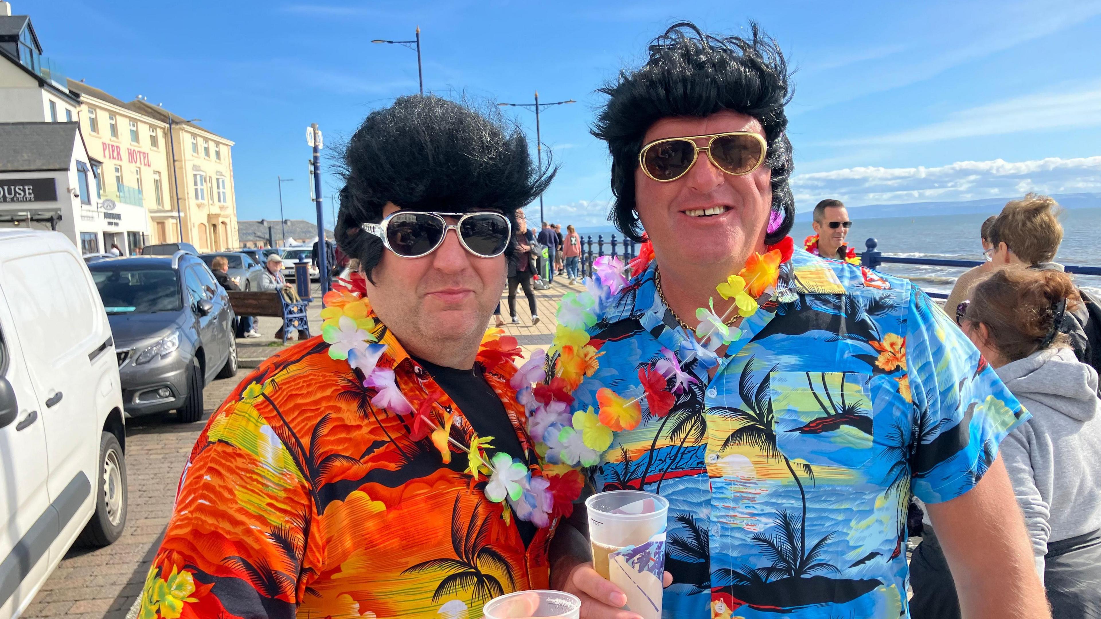 Two Elvis impersonators in wigs and Hawaiian shirts 