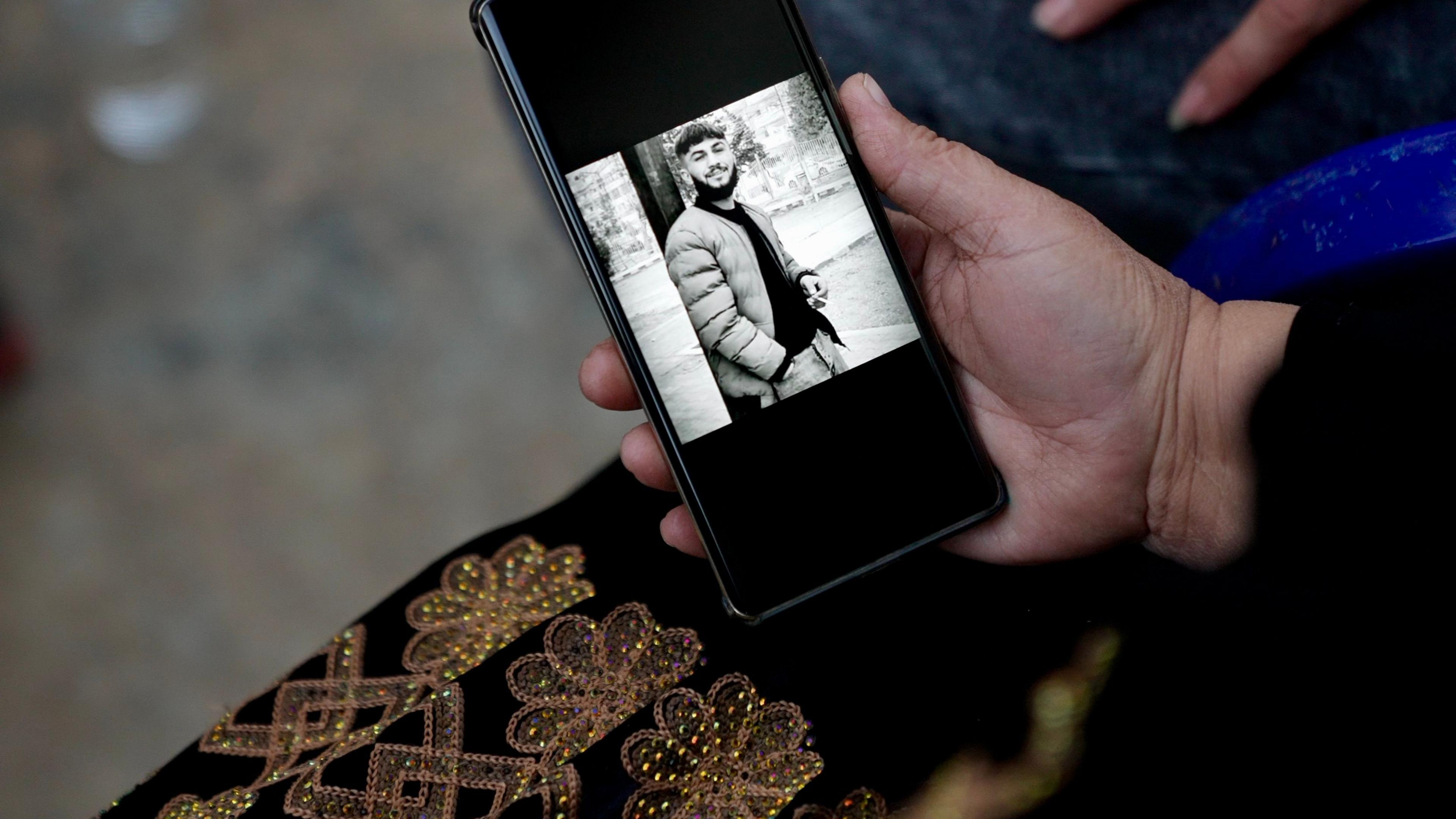 Walid's mother holds out her phone showing a black and white image of him