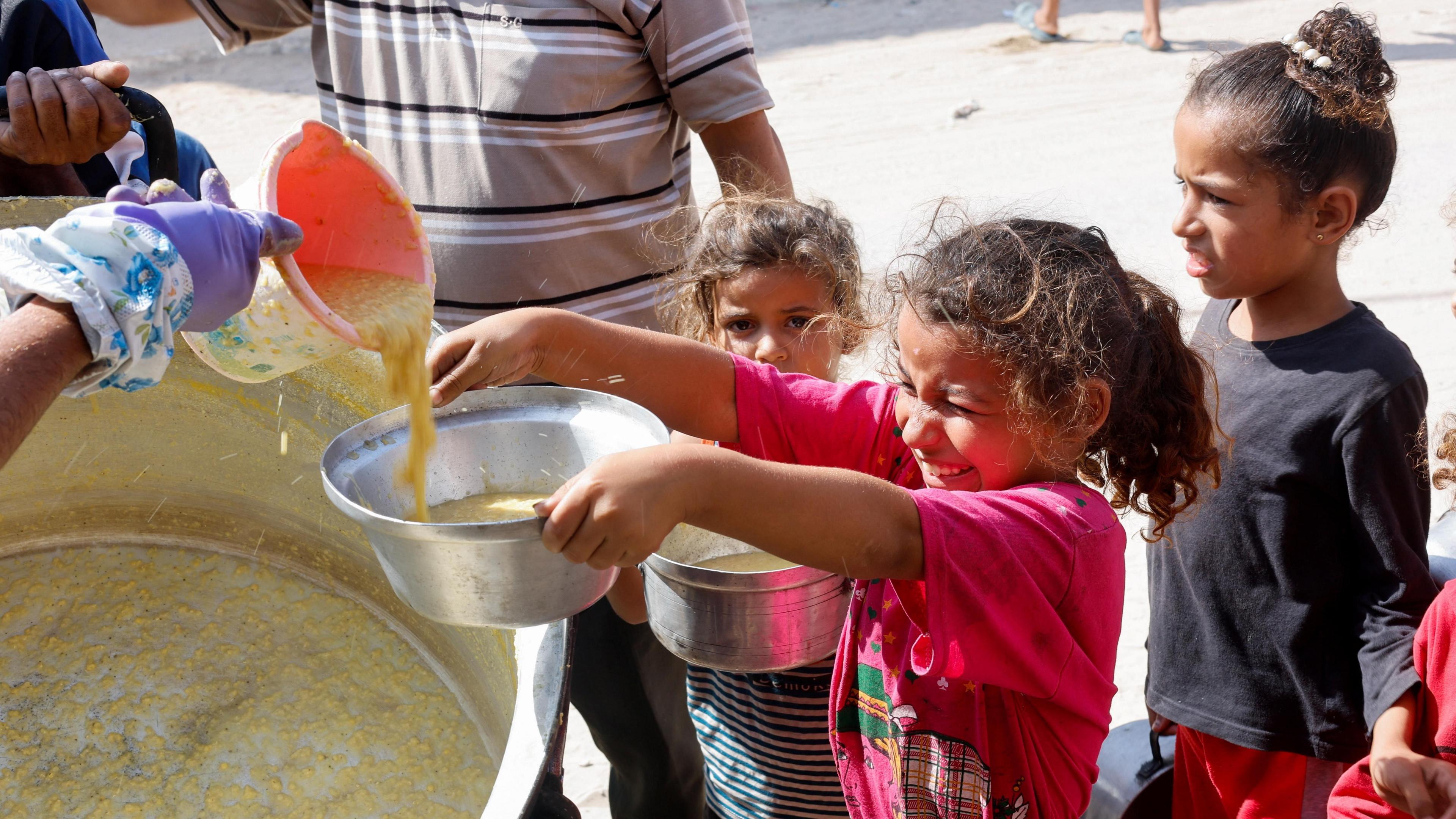 Palestinian girls receive a food handout in Khan Younis, southern Gaza (16 October 2024)