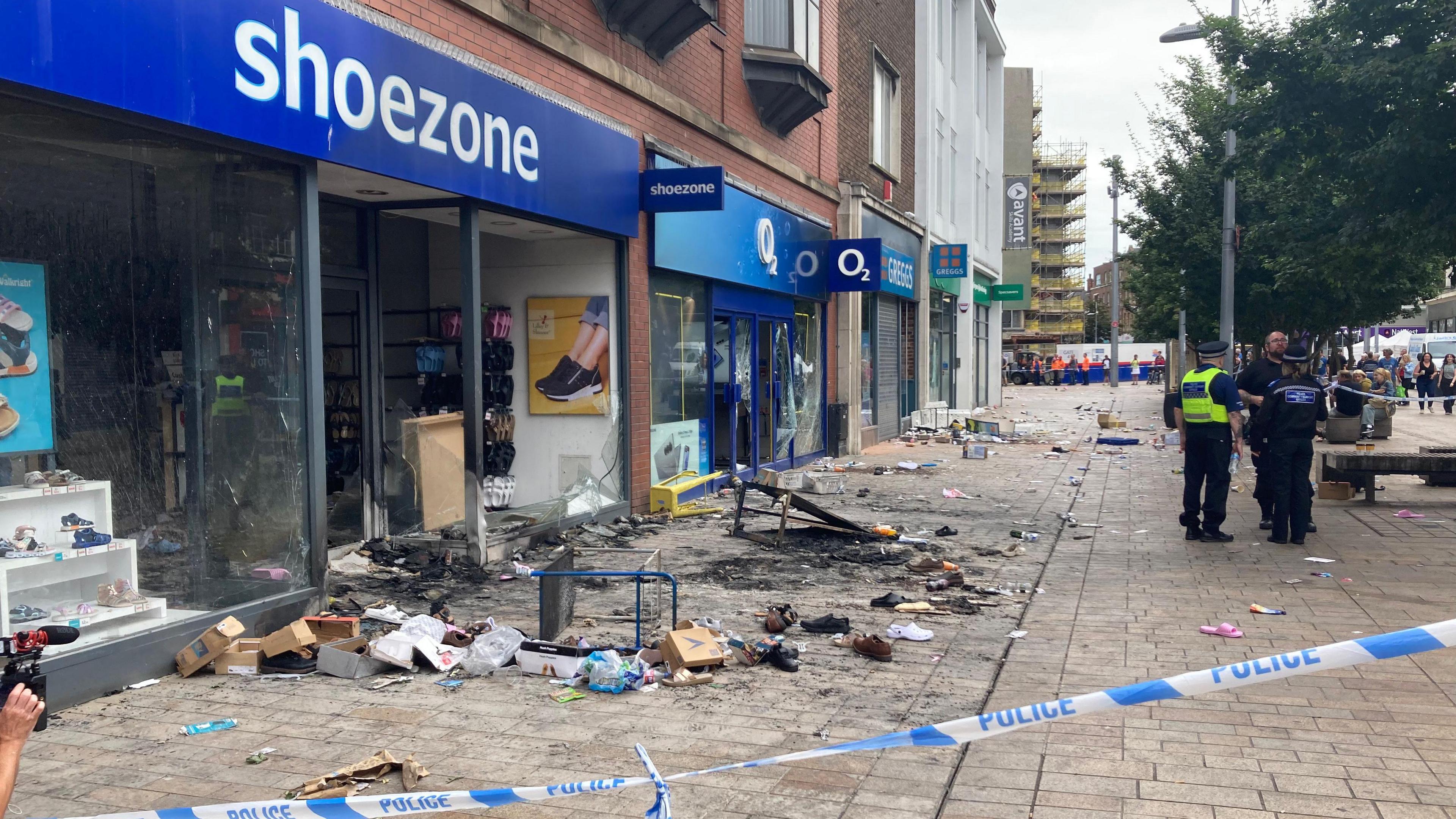 Shoezone shop in Hull city centre. It has a blue sign with white writing and a burnt out doorway following a blaze on Saturday evening. Boxes and shoes are littered across the front of the shop.