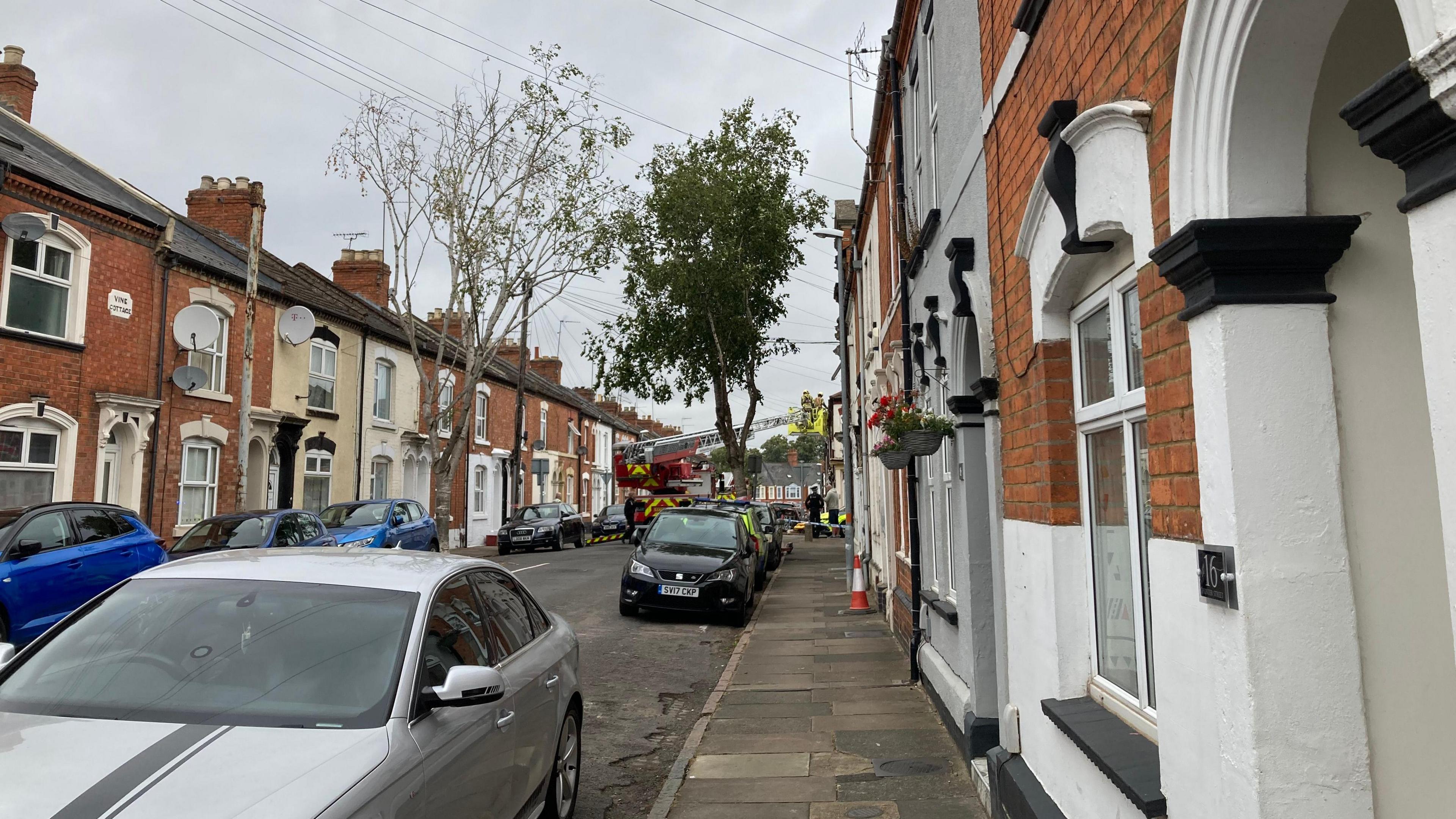 A fire crew up a ladder tackling a fire in a terraced house