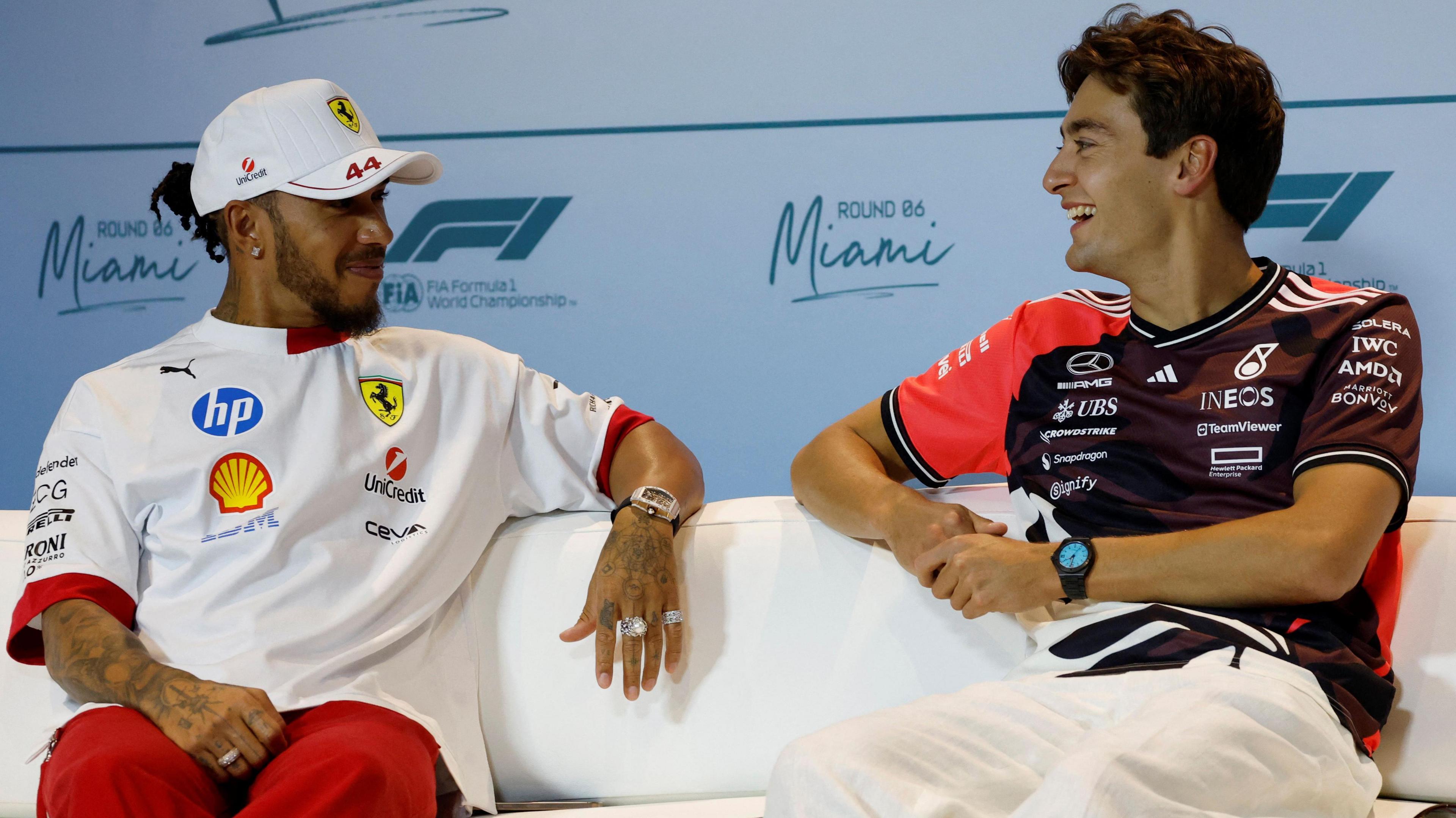 Lewis Hamilton and George Russell smile while talking to each other at a Miami Grand Prix news conference