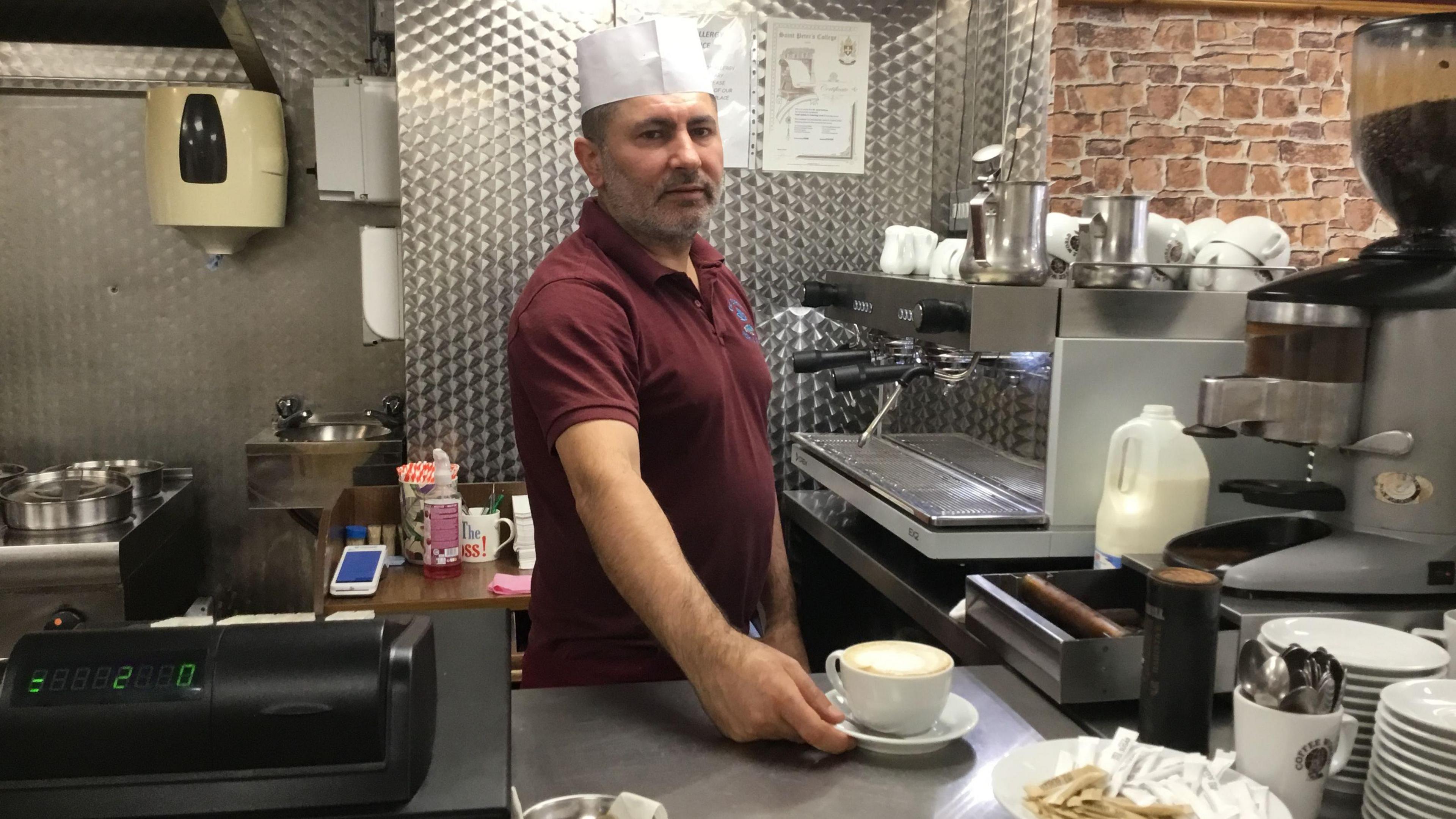 George Sarimalz in his cafe serving a cup of coffee