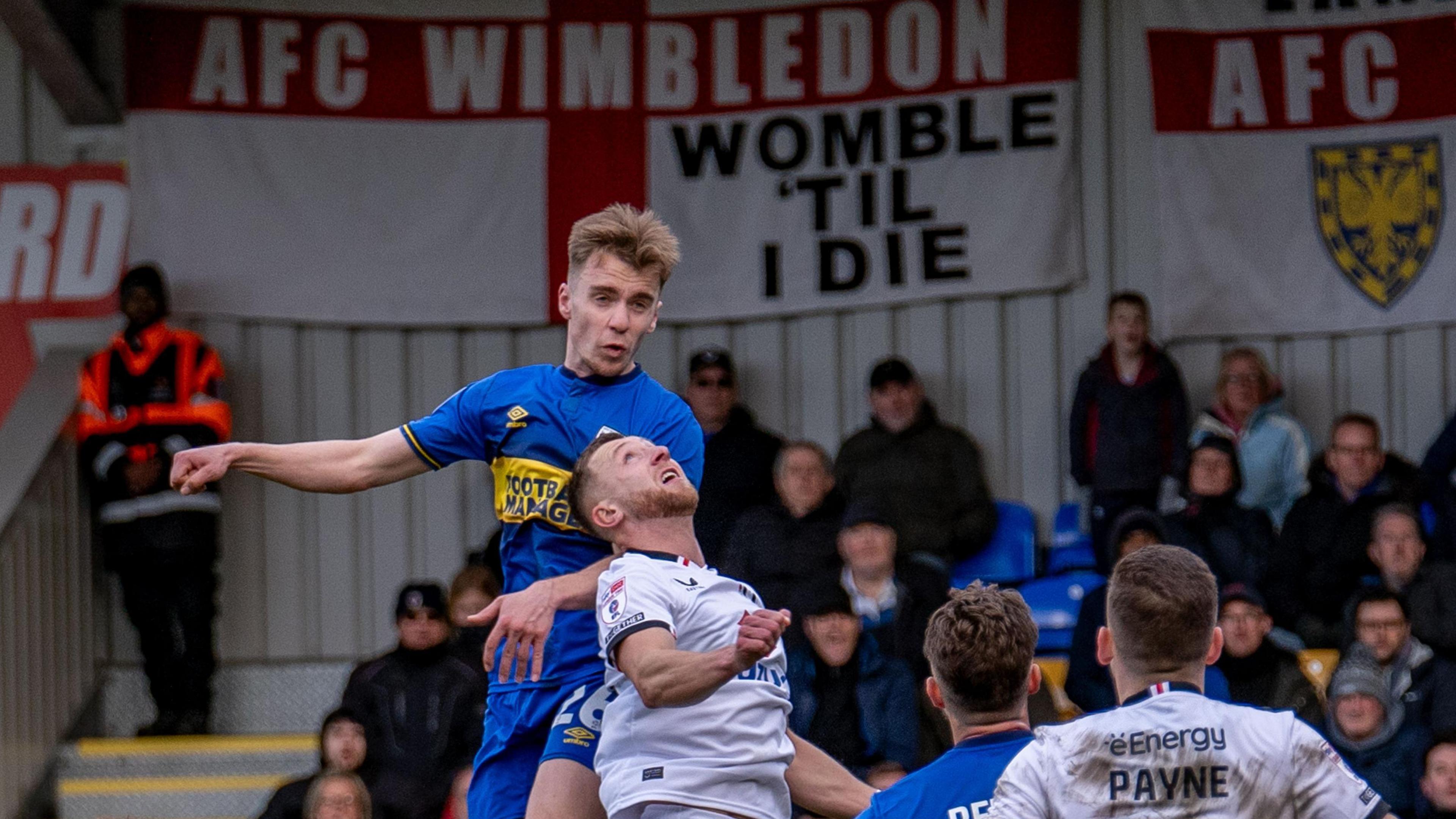 Jack Currie goes up for a header for AFC Wimbledon against MK Dons