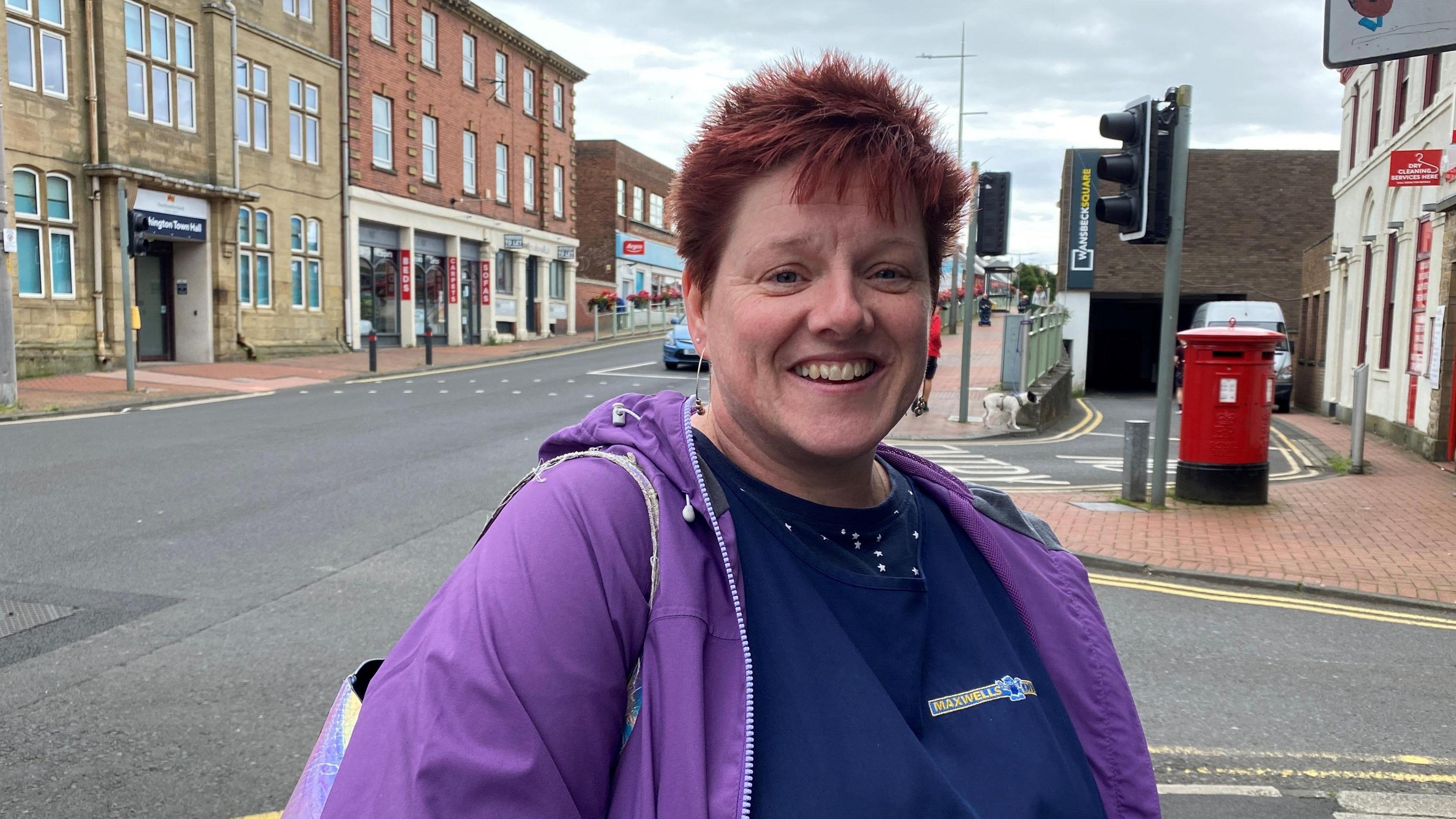 A woman in a purple jacket standing in front of the high street 