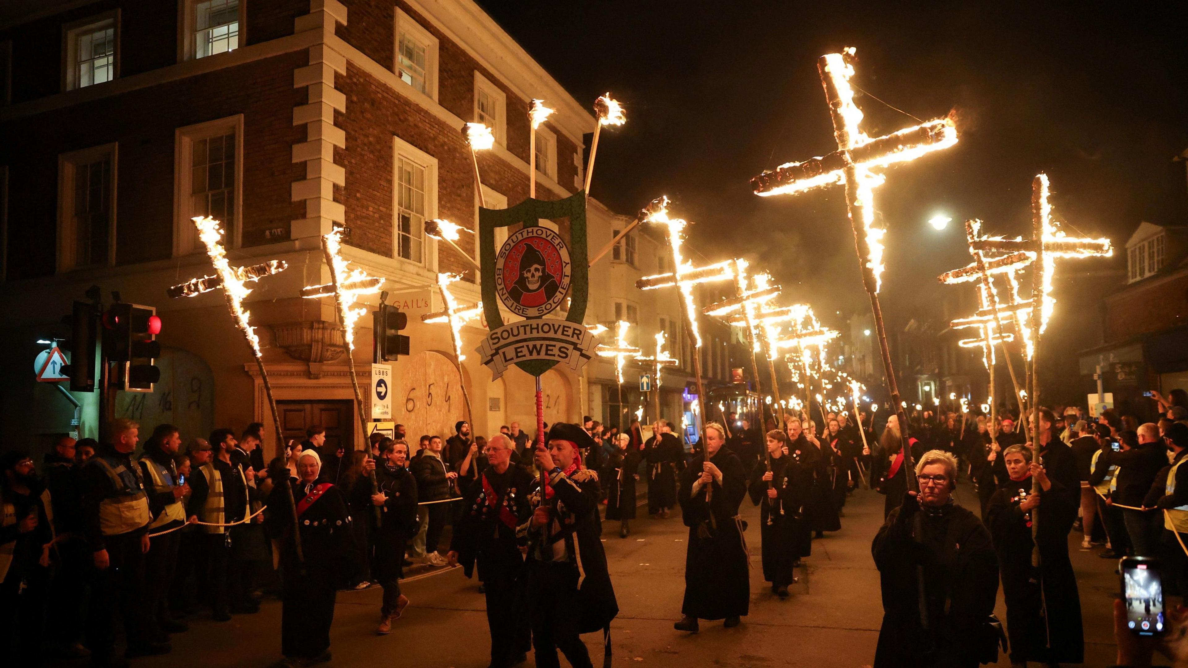 Thirteen burning crosses are carried through the crowded streets of Lewes by people wearing monastic habits.