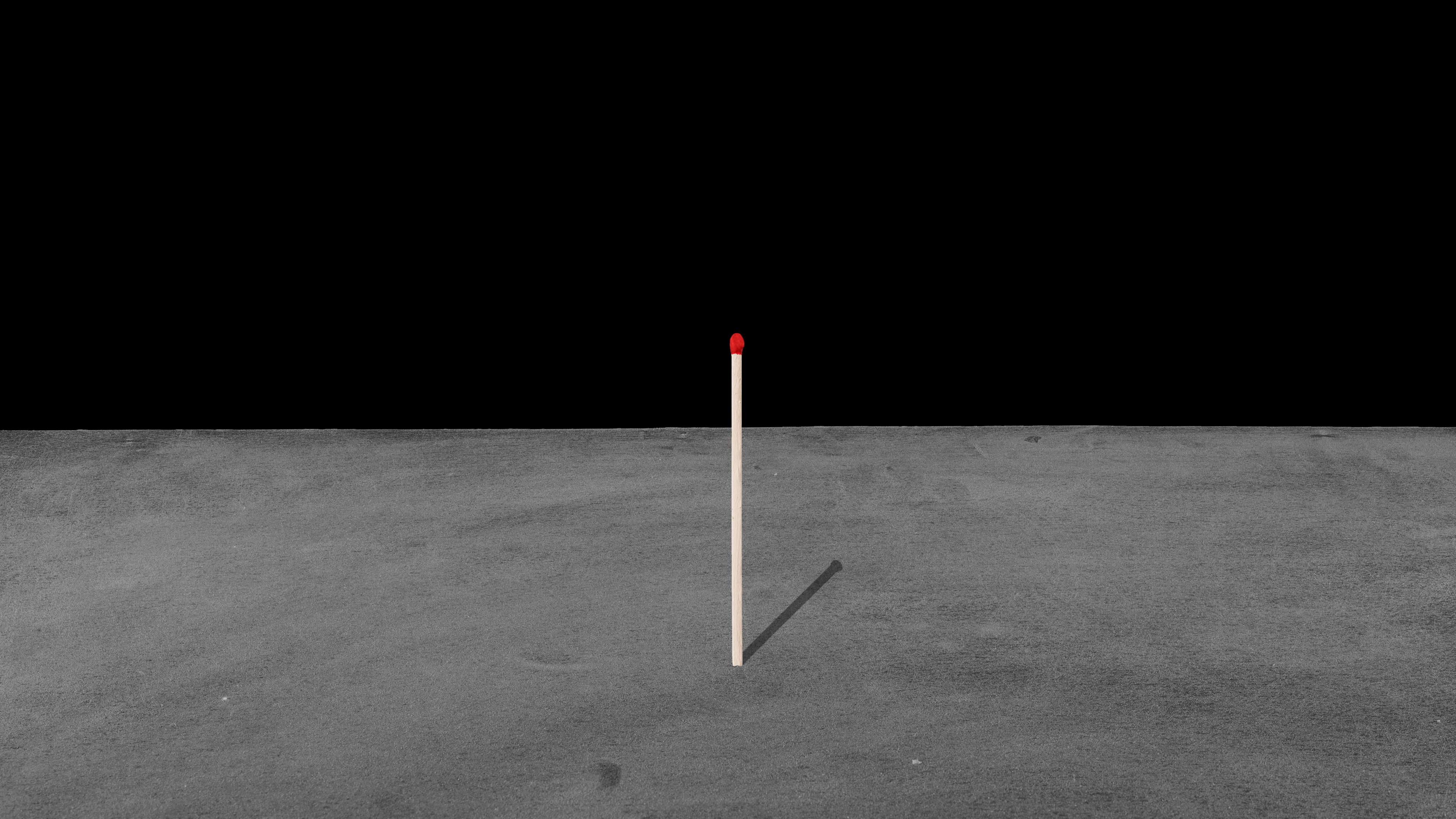 An example of Connor Daly's photography. This example shows a match stick standing upright on a grey floor with a black background.