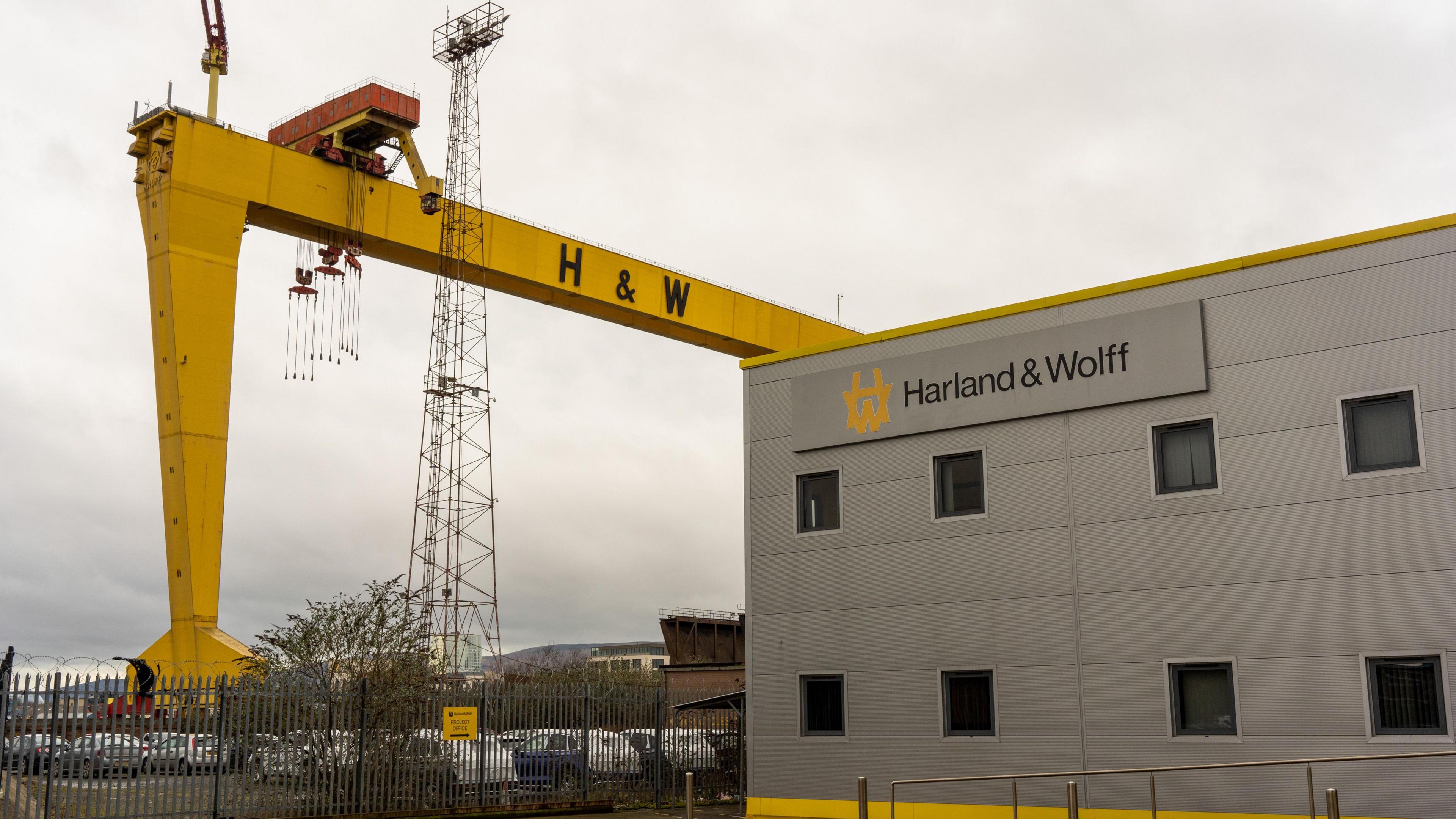 One of the iconic Harland & Wolff Samson and Goliath yellow gantry cranes near the entrance to the Harland & Wolff shipyard building. The shy is cloudy. 