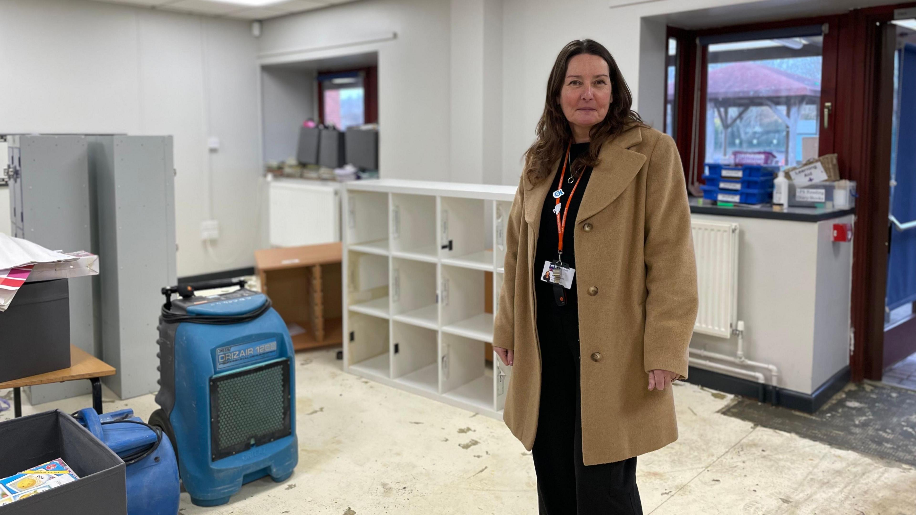 Joanne Andrews stood in a classroom where the flooring has been taken out. A humidifier is on the left 