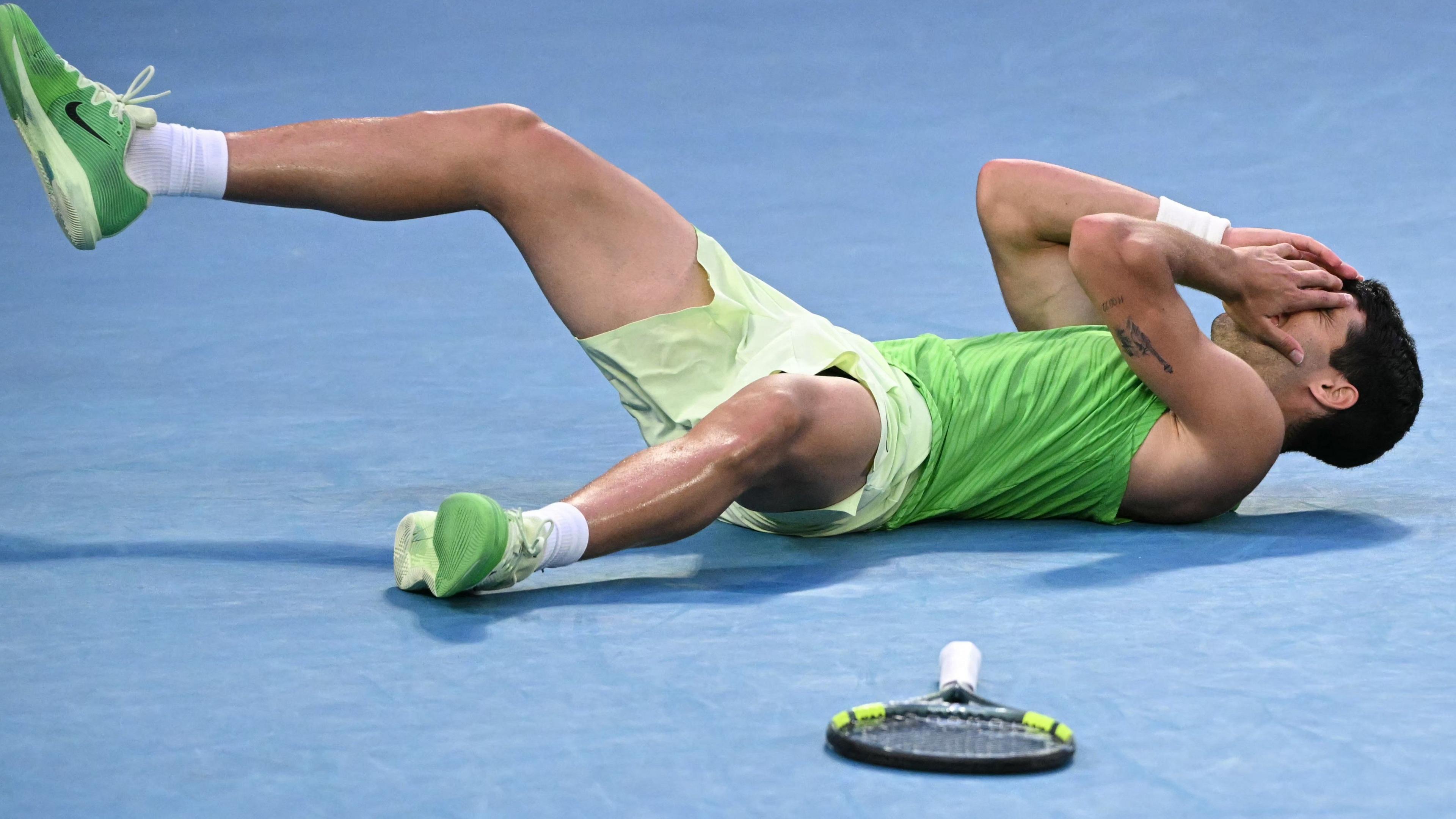 Carlos Alcaraz lays on the court in disbelief