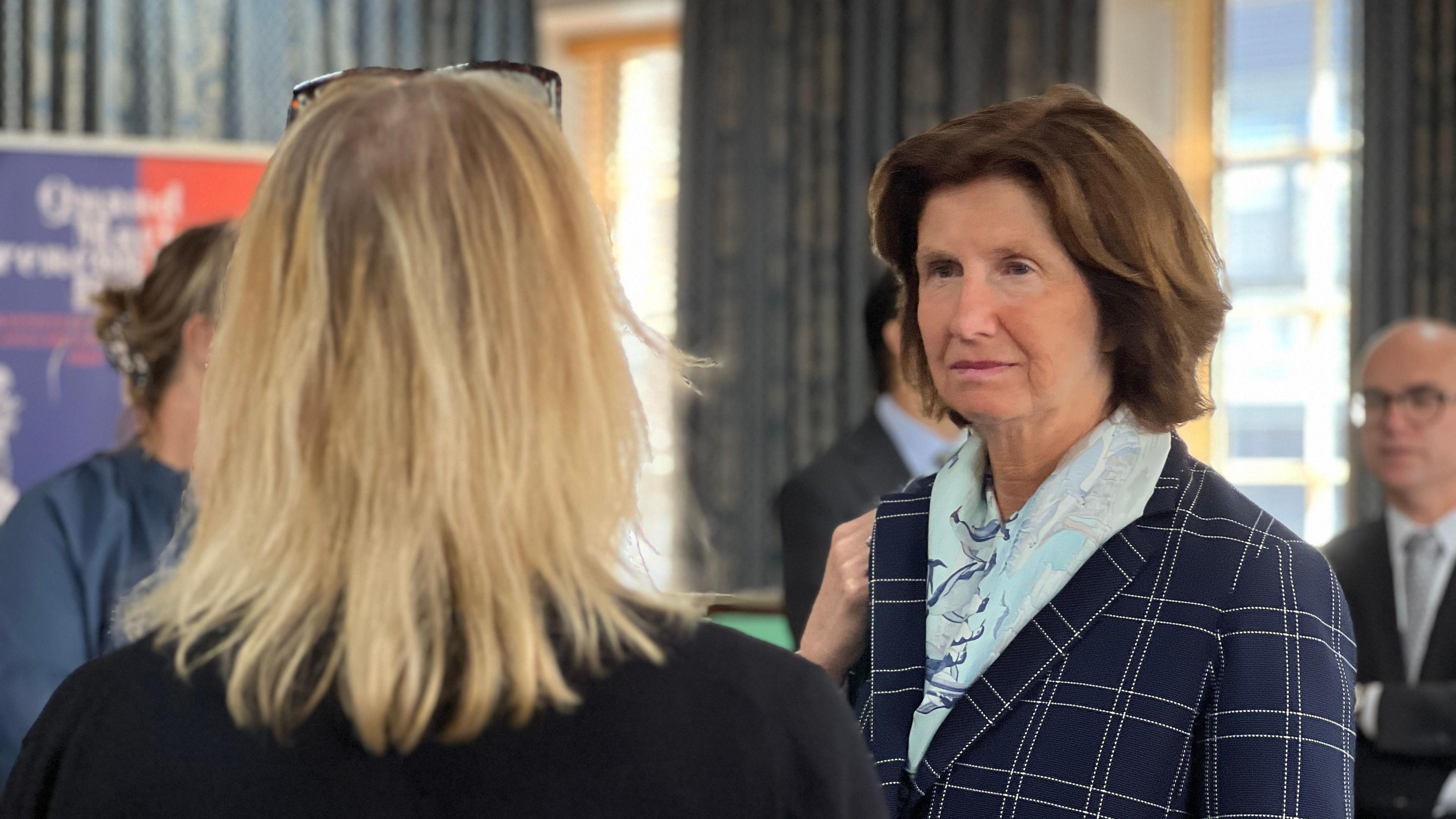 Hélène Duchêne looks at a woman in front of her at a history exhibition