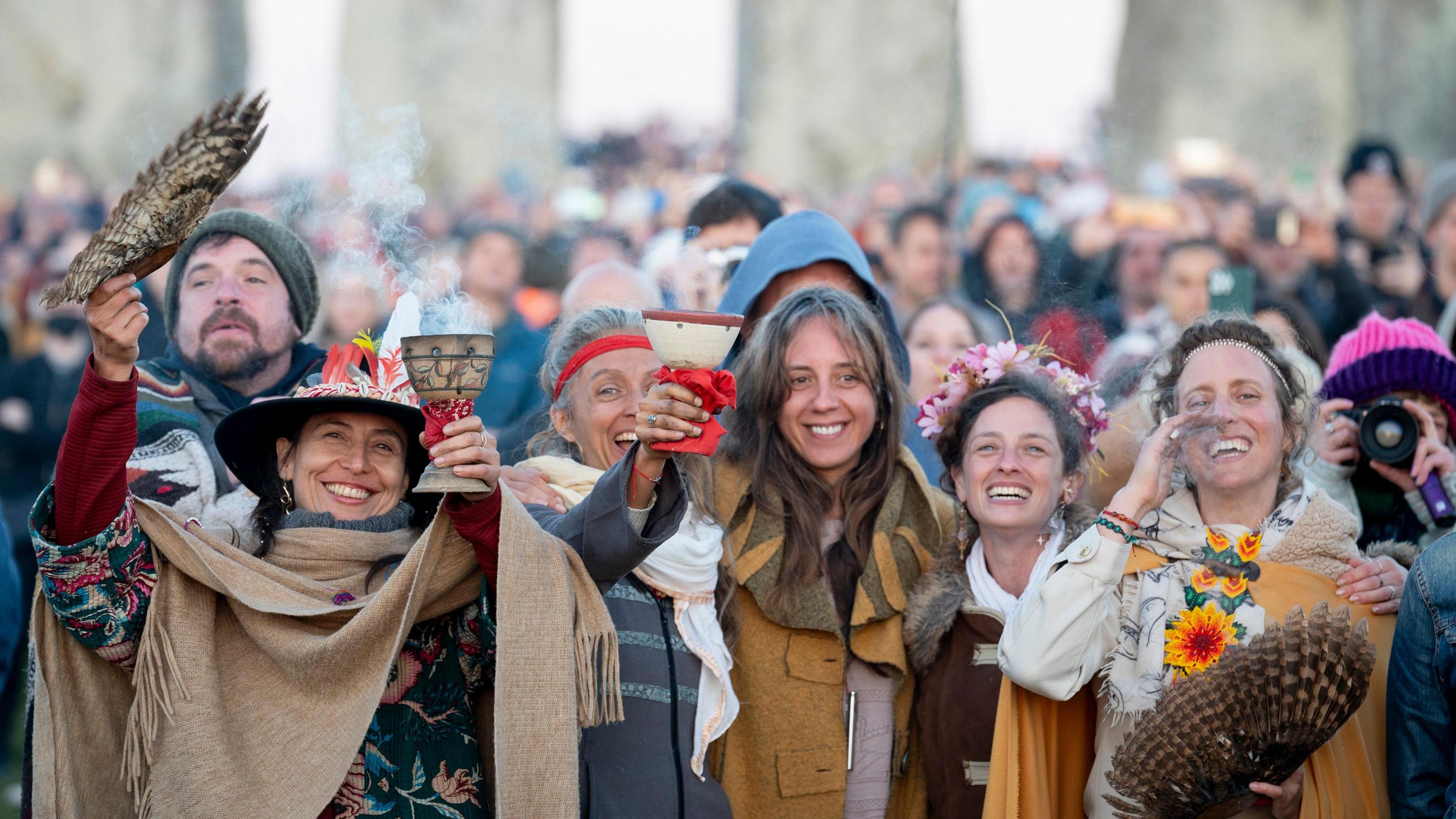 People at Stonehenge, smiling and raising a goblet as the sun rises at Stonehenge in Wiltshire