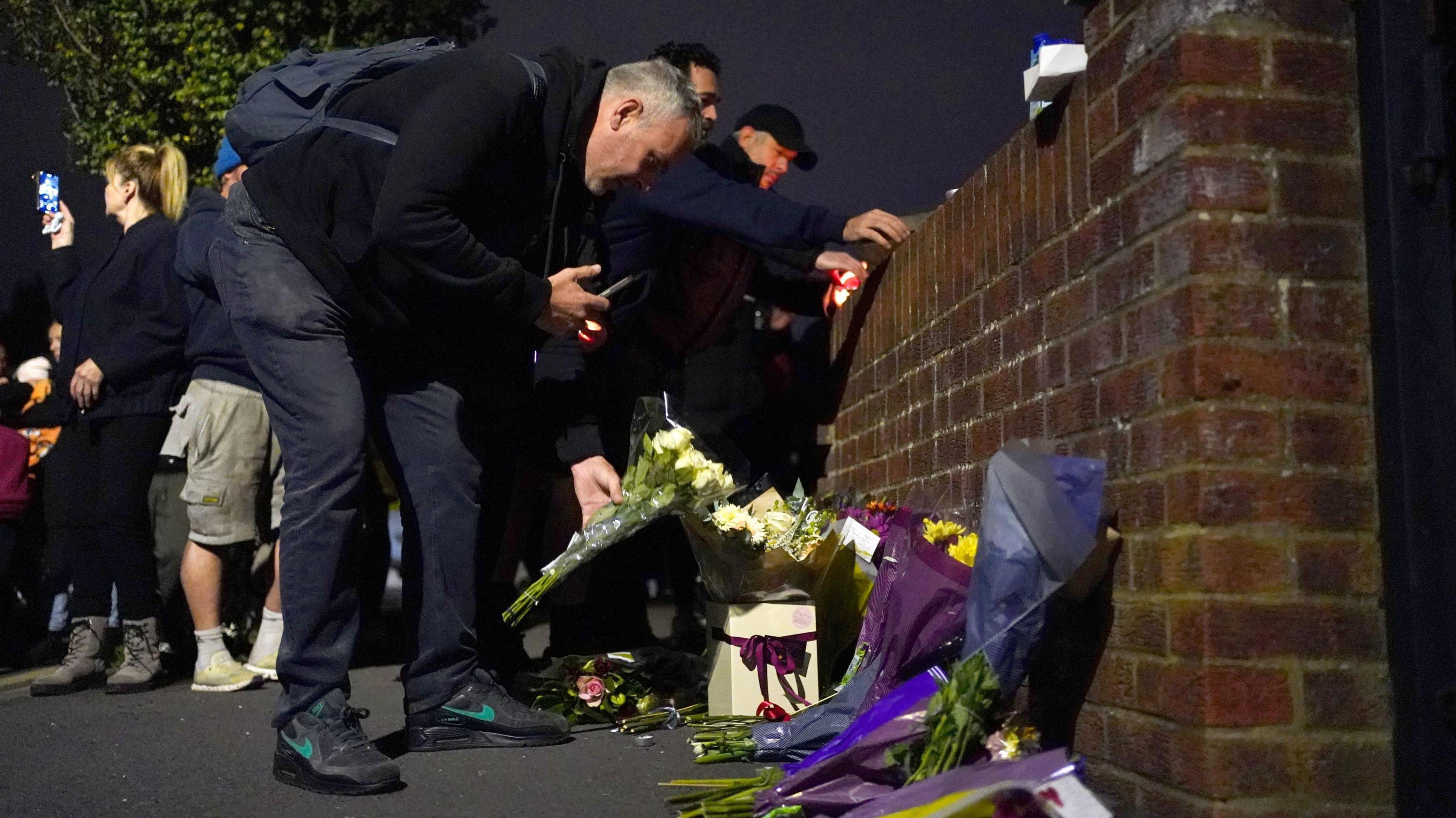 People lay flowers near Midhurst Gardens in Uxbridge.