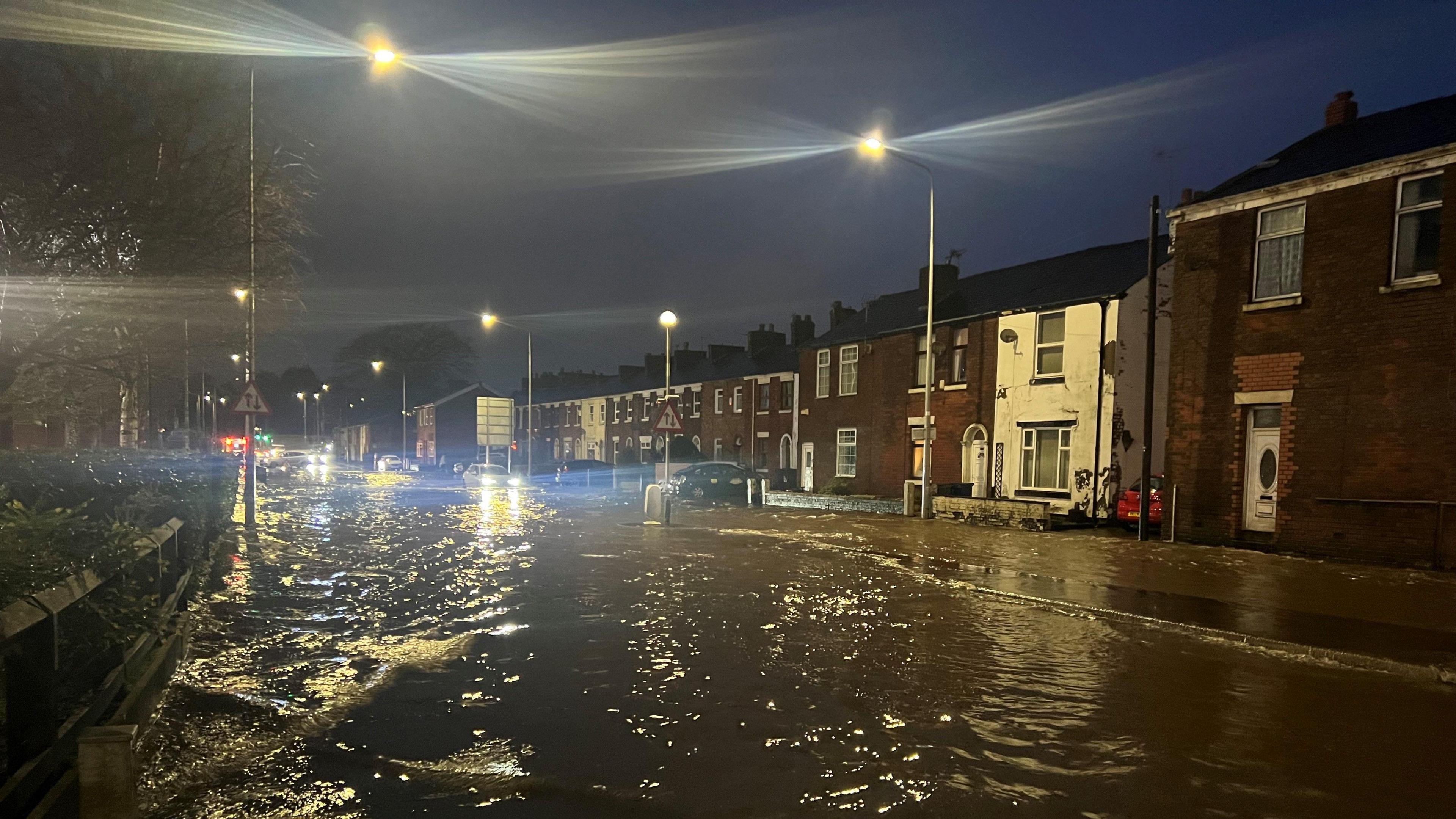 A row of houses surrounded by muddy flood water 