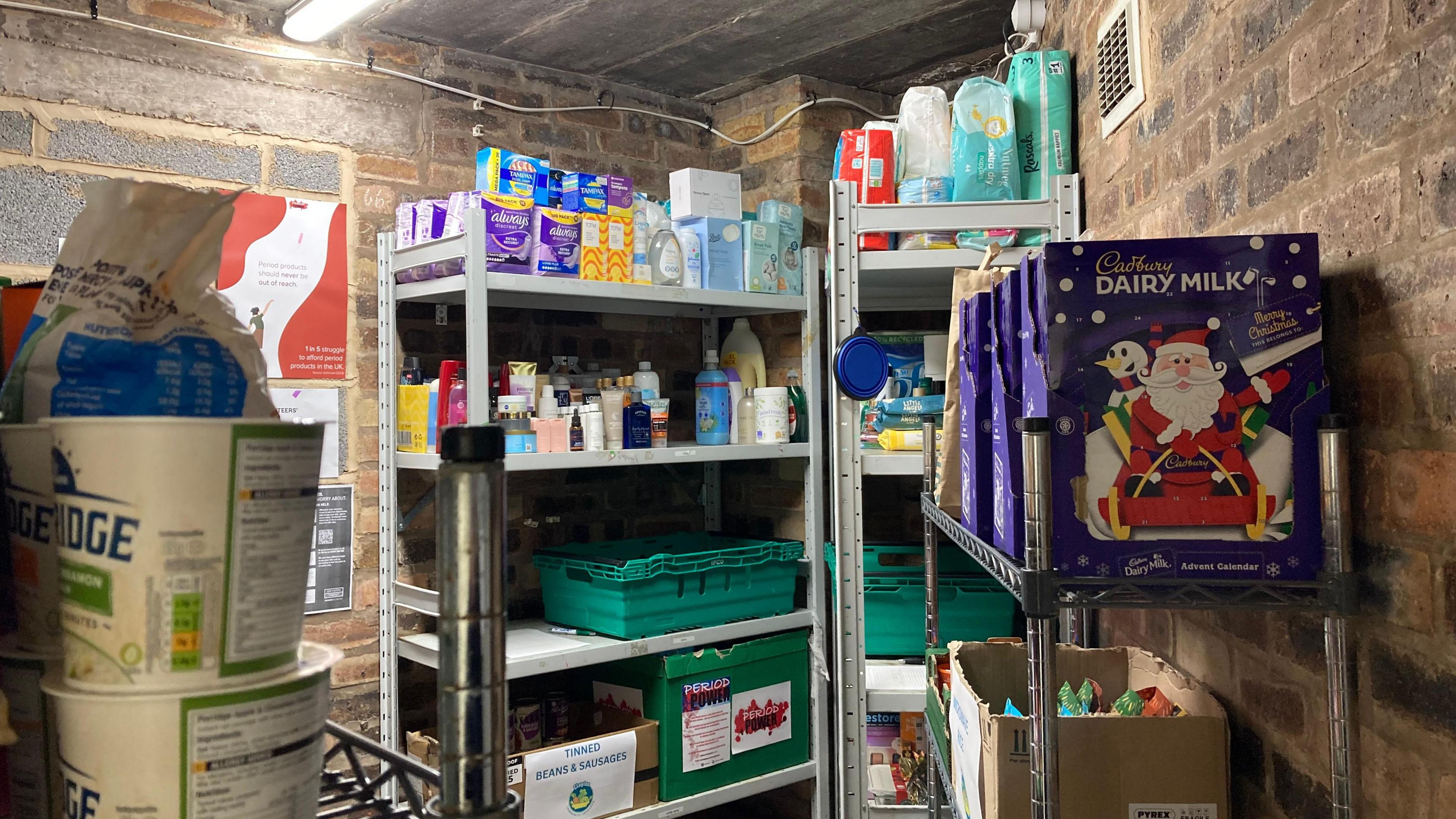 A store room in the back of a shop with shelves full of items including essentials and advent calendars.