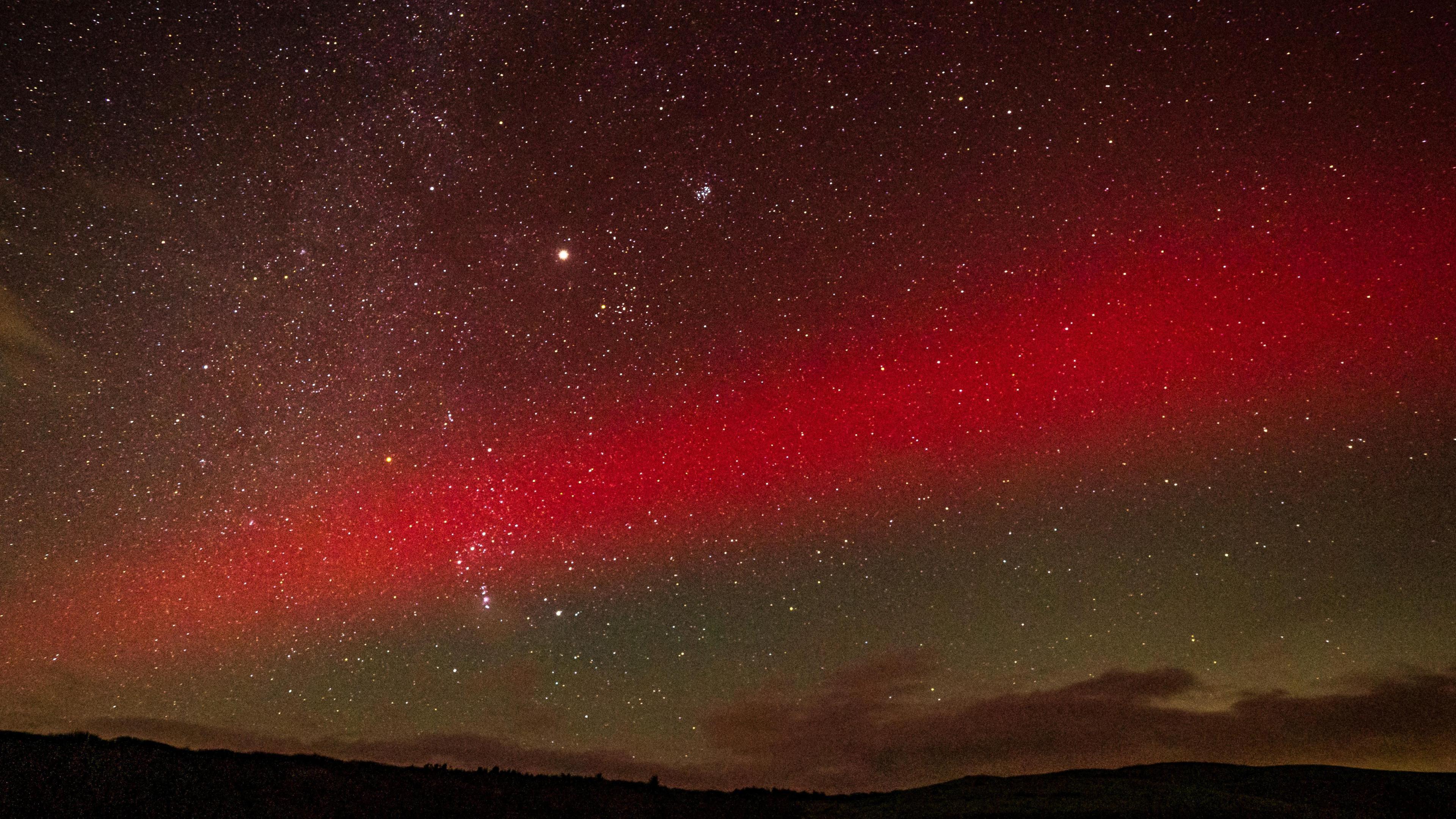 red ribbon of the northern lights streaking across the night sky