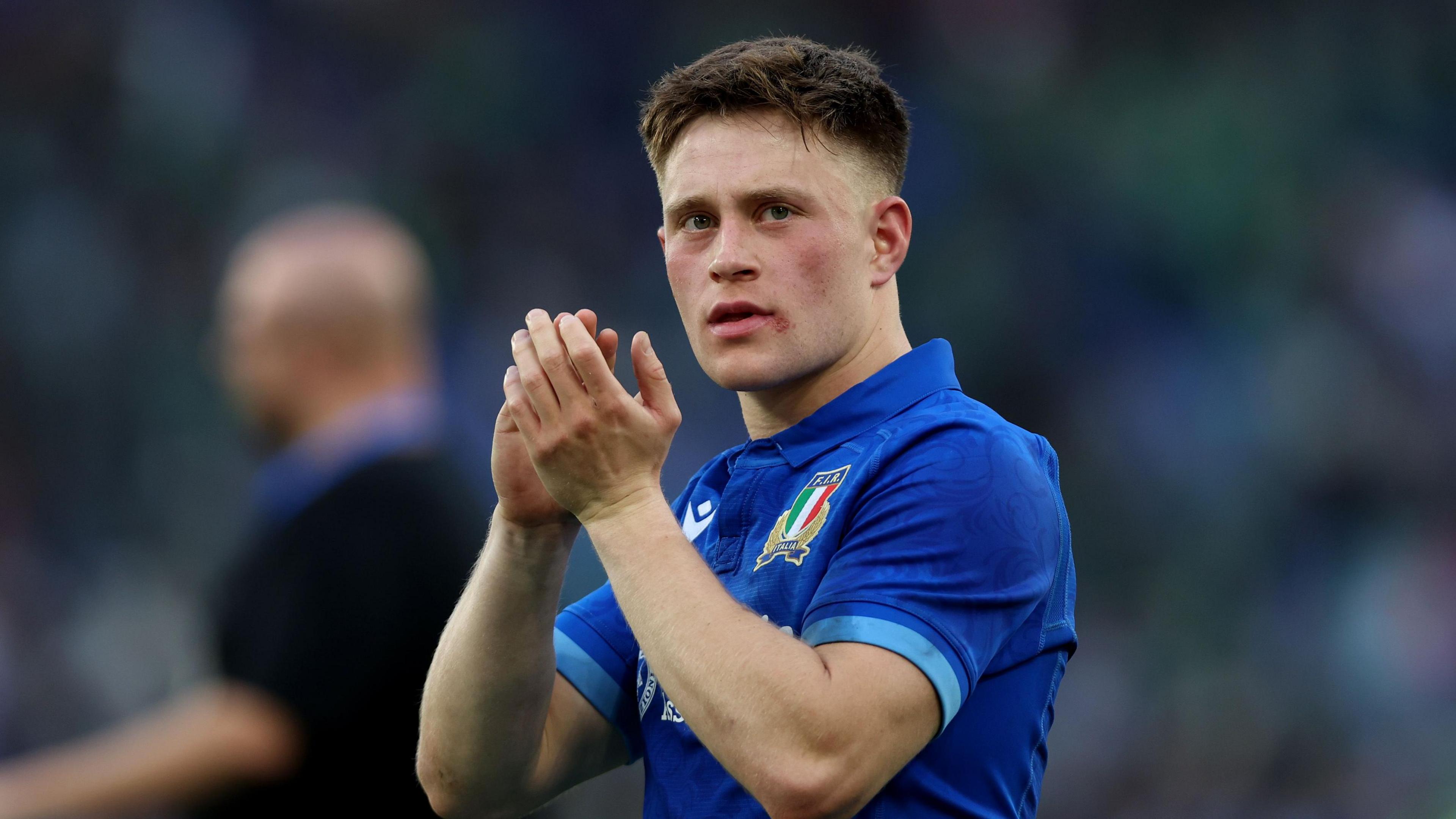 Stephen Varney wearing an Italian rugby shirt, and applauding fans.