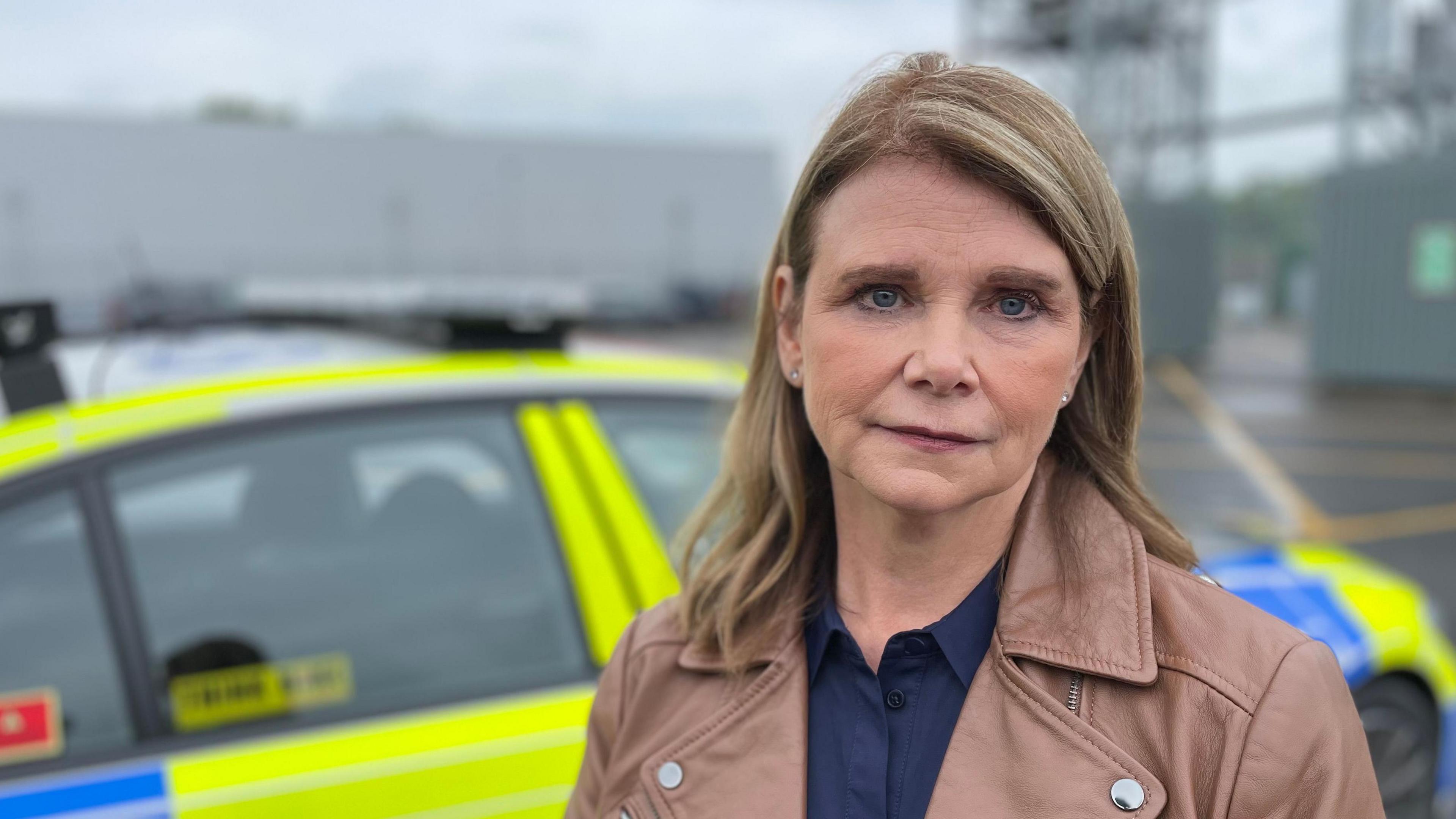 A woman standing in front of a police car