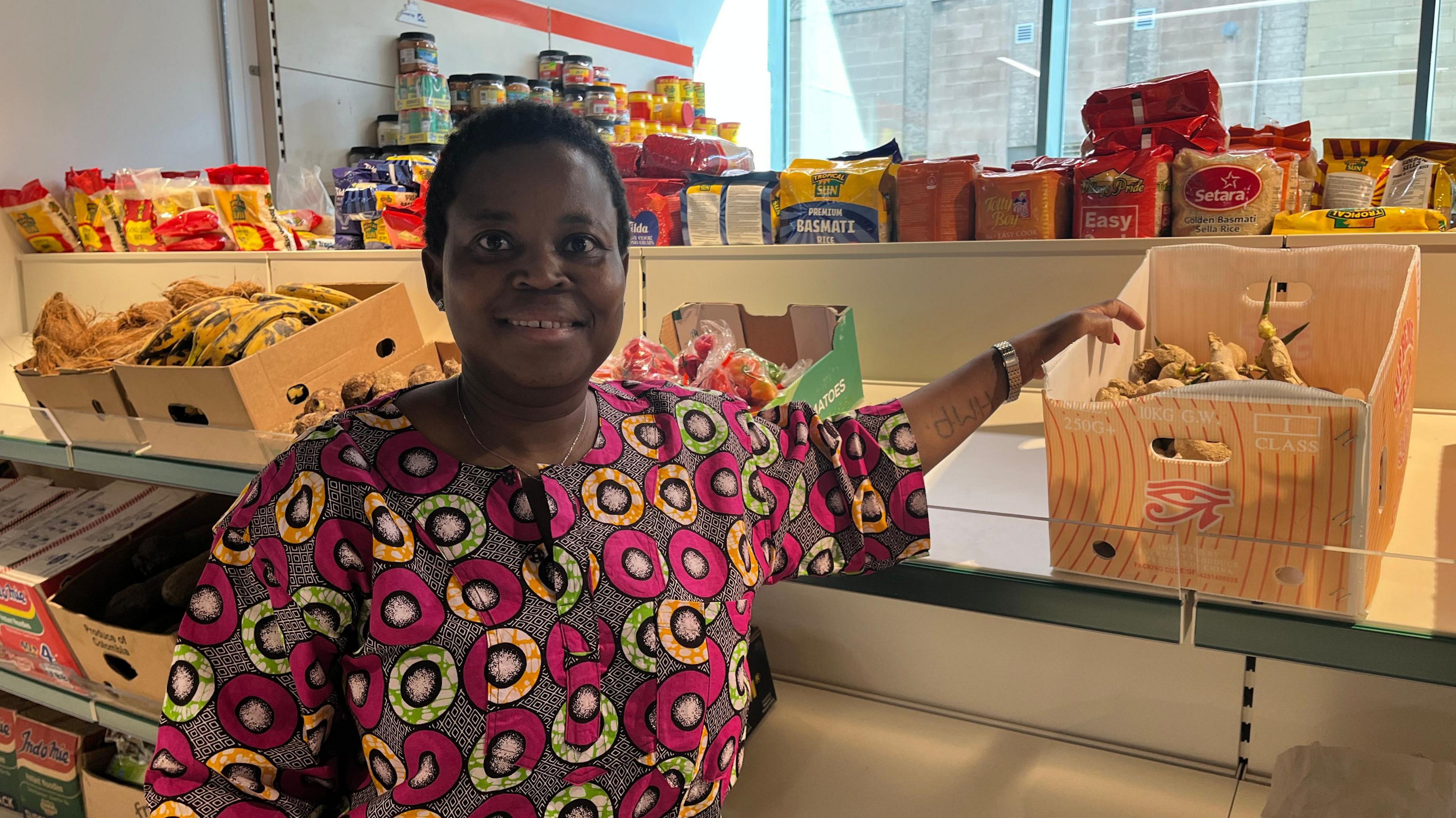 Woman smiling with food shop behind her.