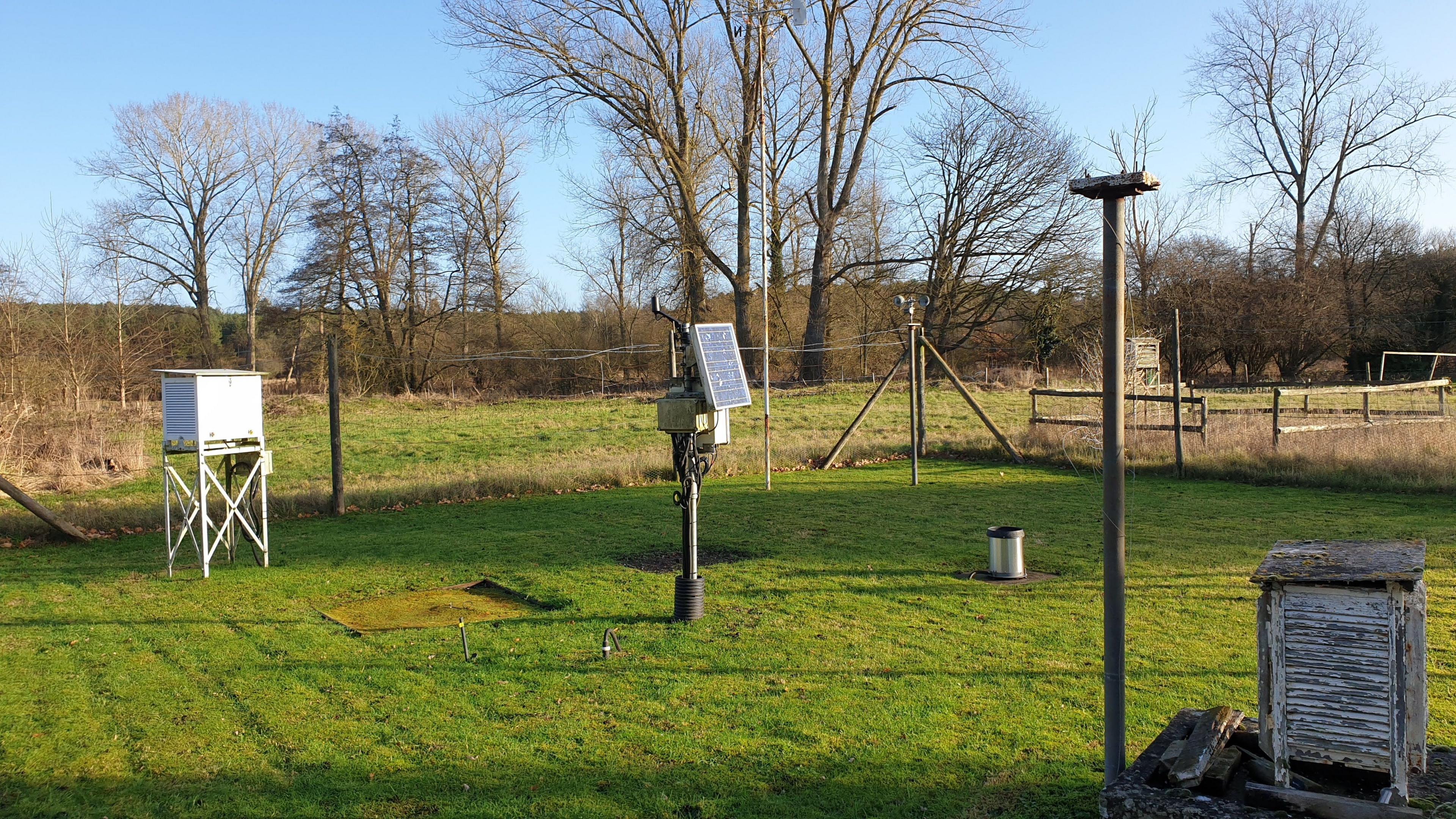 Fence around a green patch of grass featuring with weather measuring equipment