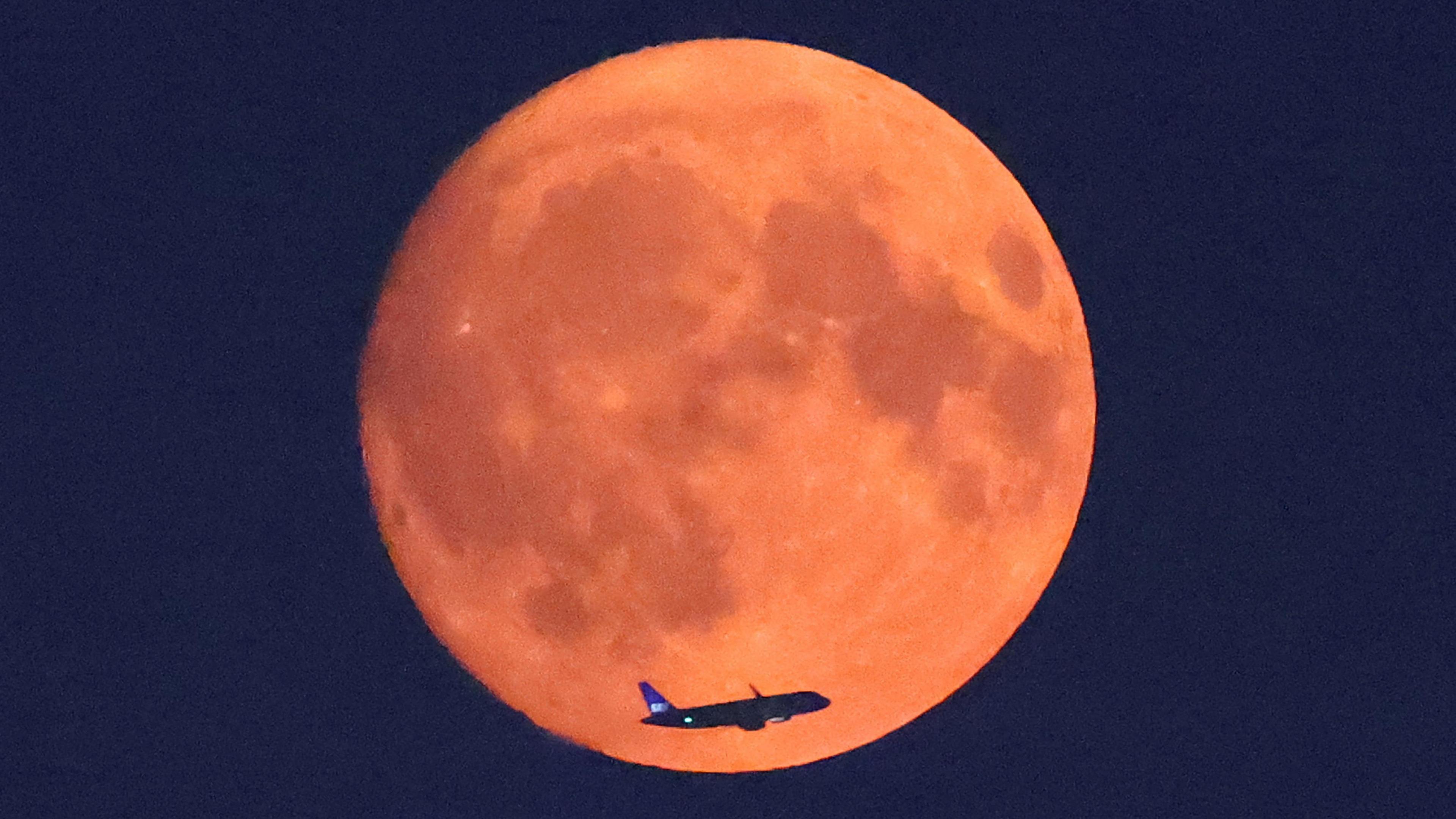 A plane flies across the red Supermoon over London in the United Kingdom. 