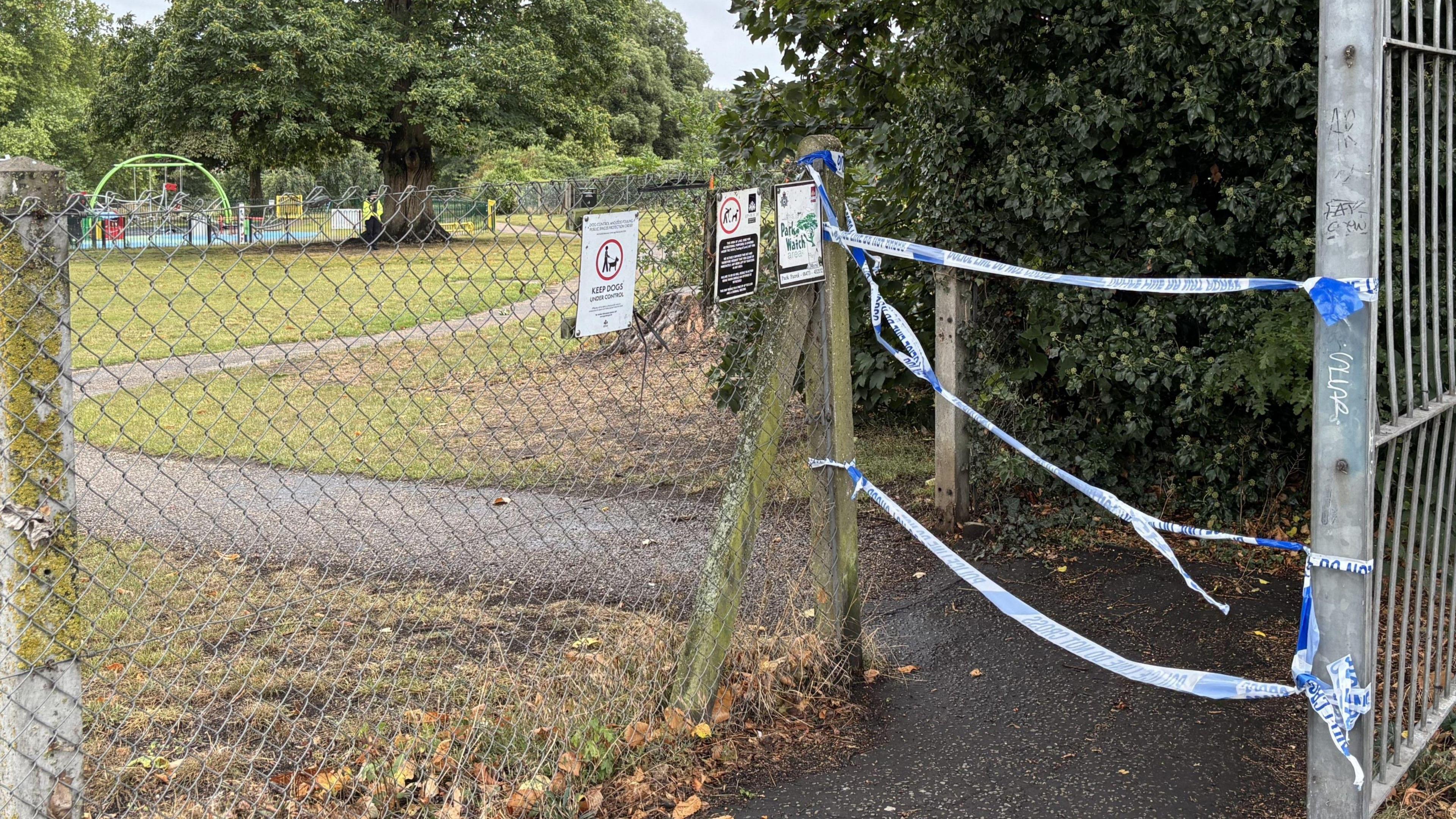 An entrance into a park is blocked by police tape.