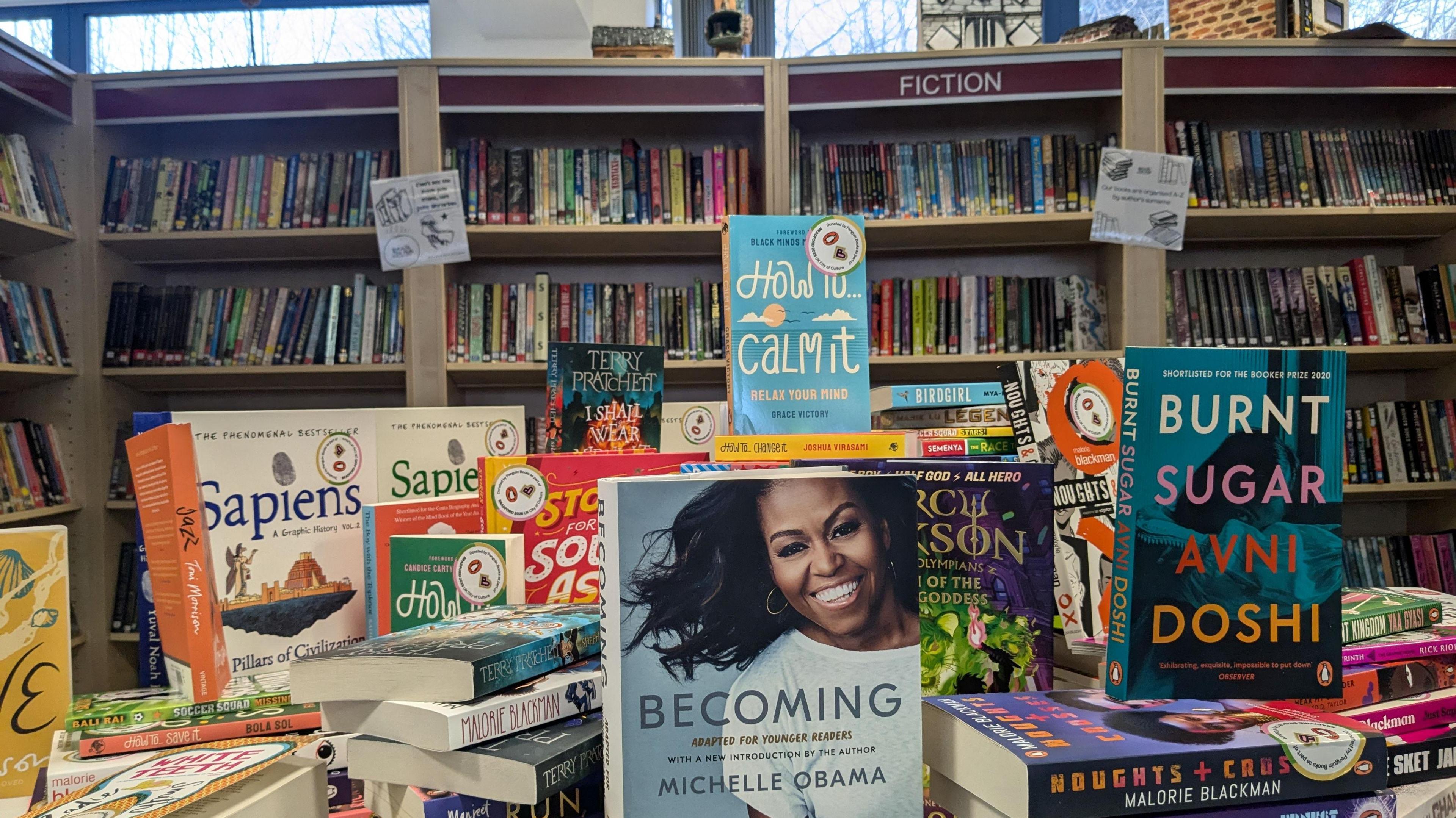 A pile of diverse and colourful books in a library. 