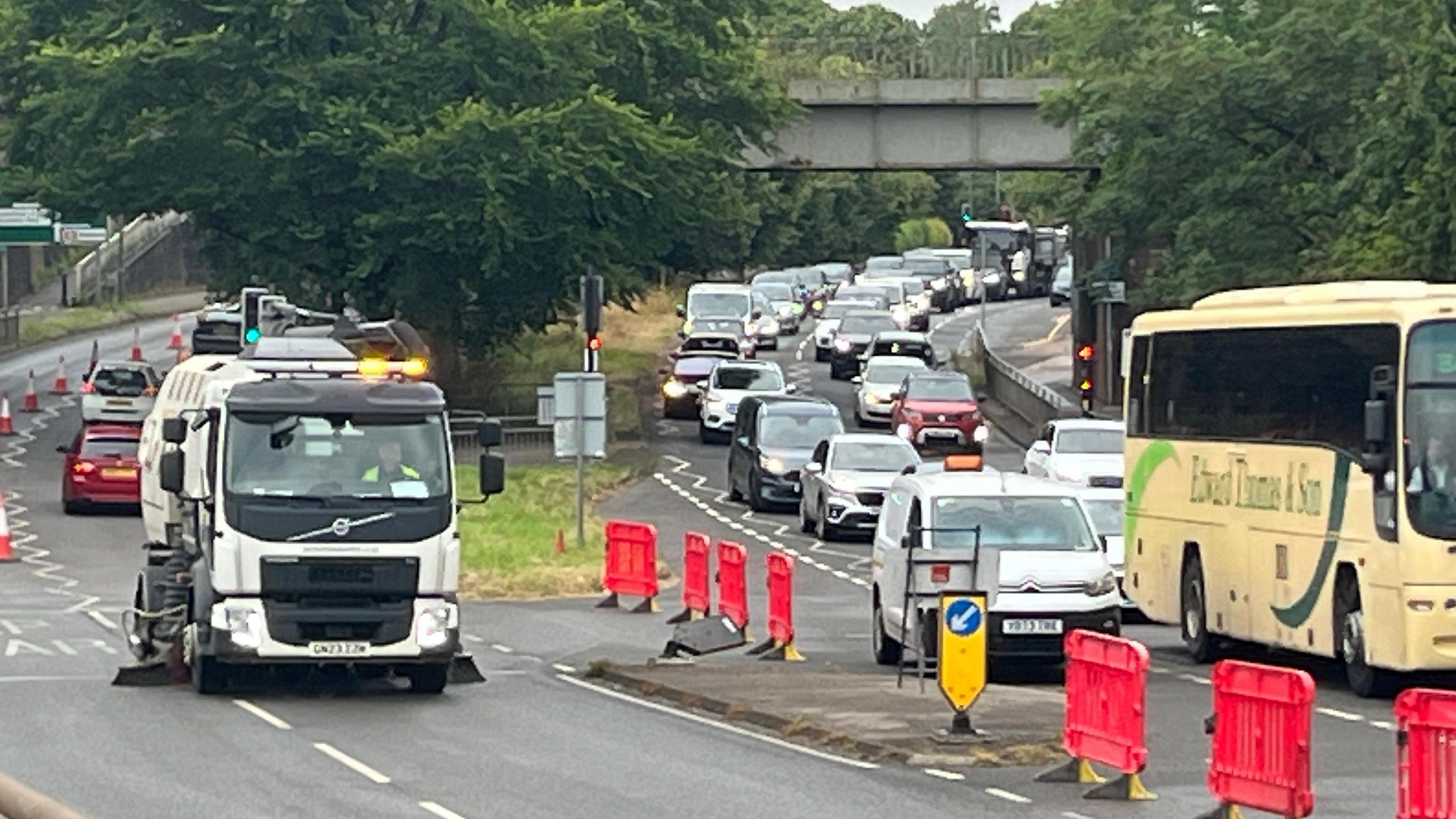 A street cleaning vehicle on the A24, with queuing traffic on the other carriageway