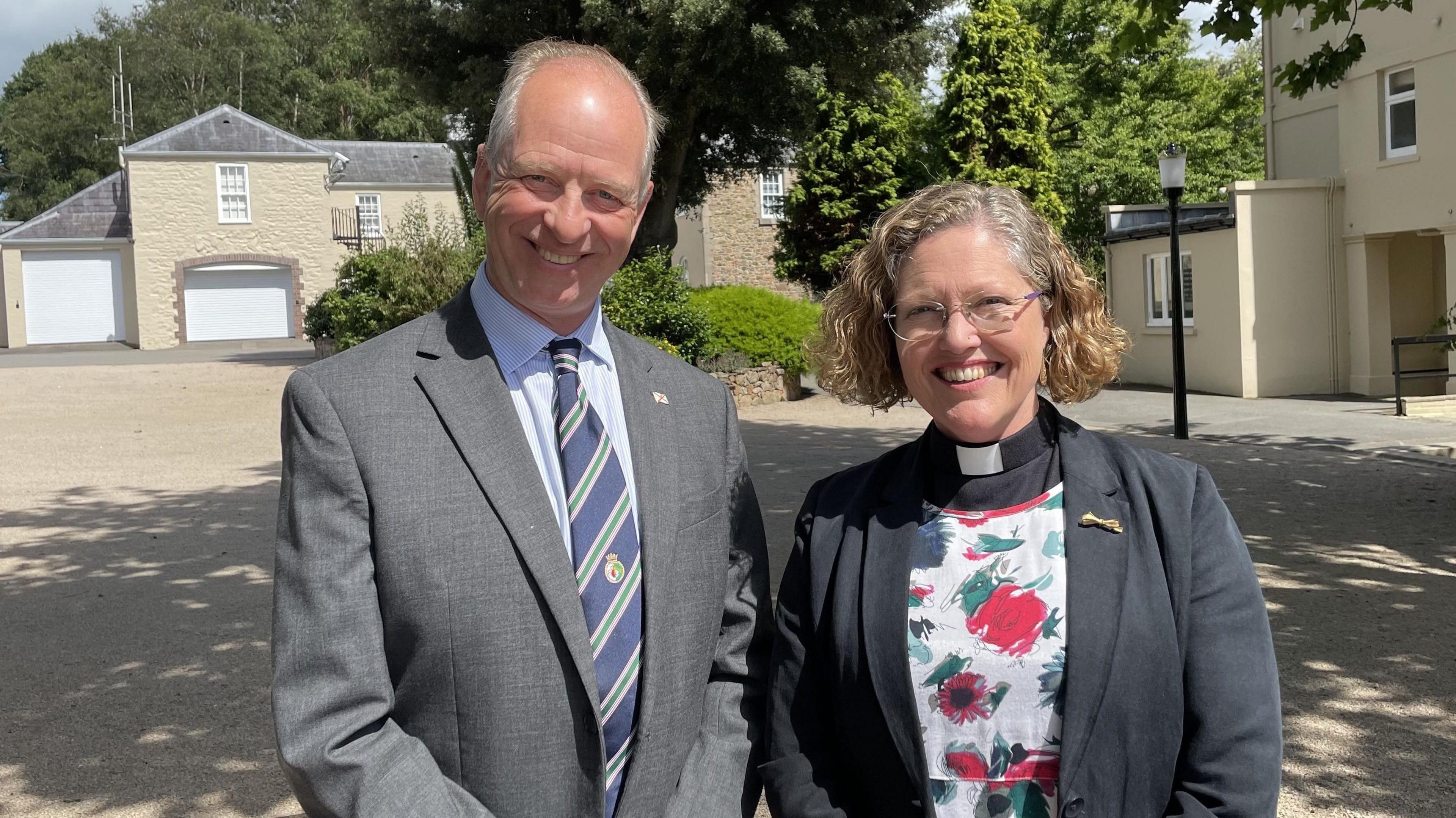 Jersey's Lieutenant Governor, Jerry Kyd, wearing a suit stands next to the Rev Sarah McClelland, a woman with glasses wearing a rector's dog collar.