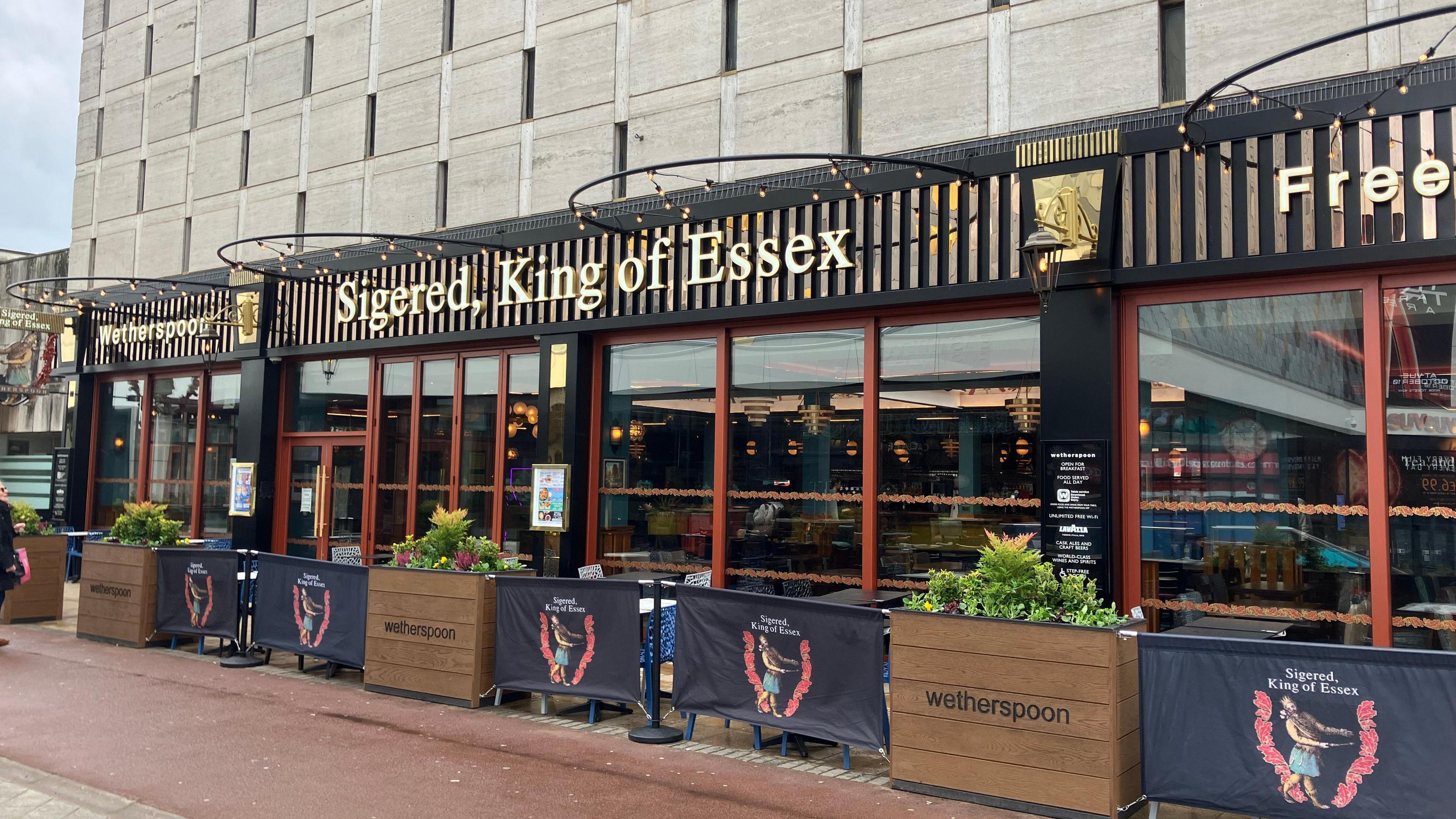 A wide shot of a pub with a slightly shiny, red and gold colour scheme.