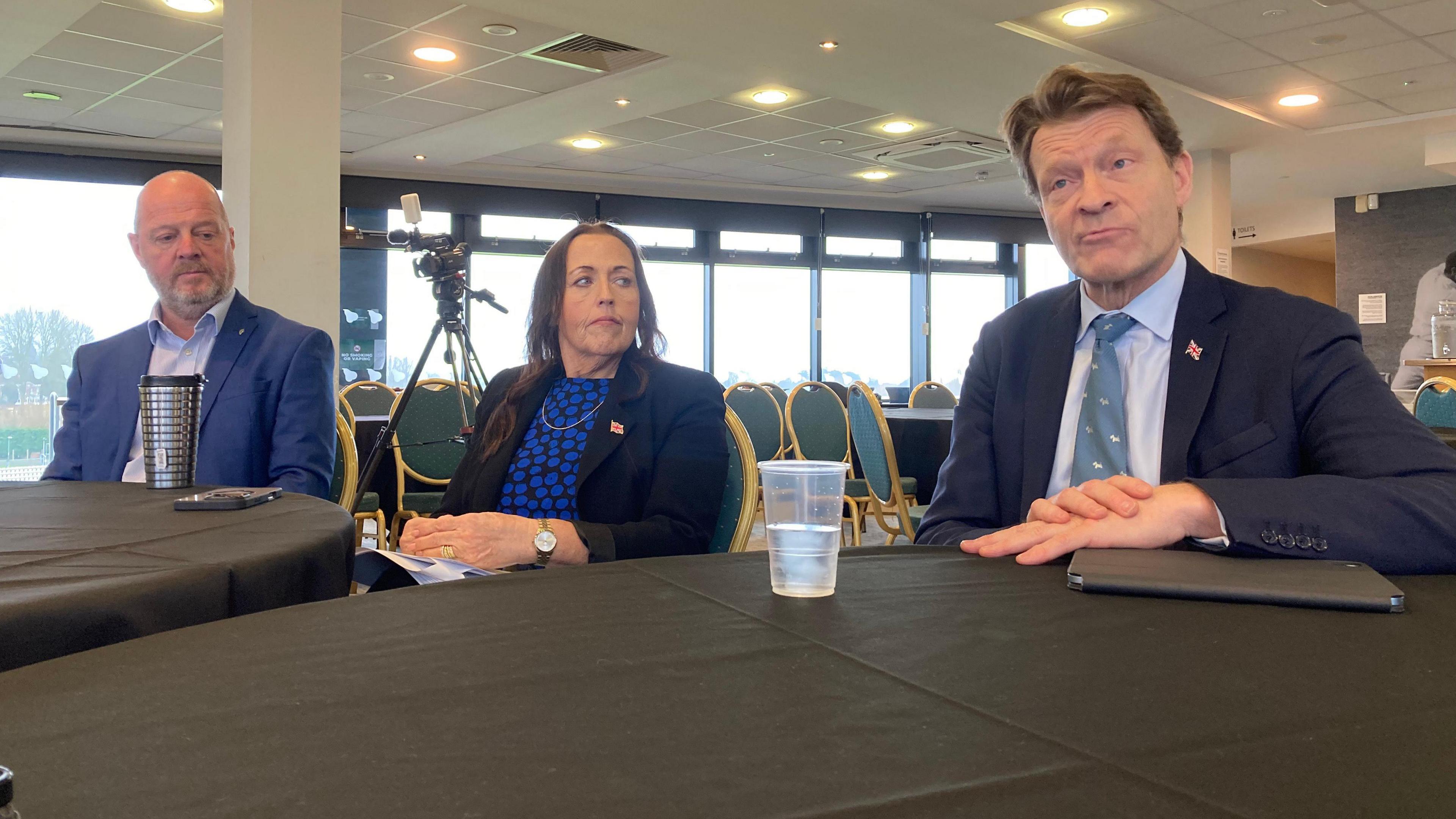 Three people sat behind a table at a press conference, including the leader of Worcestershire County Council, Cllr Jo Monk, and Richard Tice, deputy Reform UK leader.